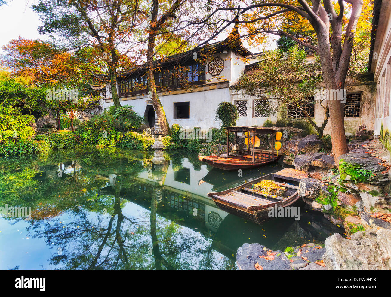 Tradizionale storico giardino botanico nella città cinese di Suzhou vista interna di architettura attorno ancora stagno con barche e alberi. Foto Stock