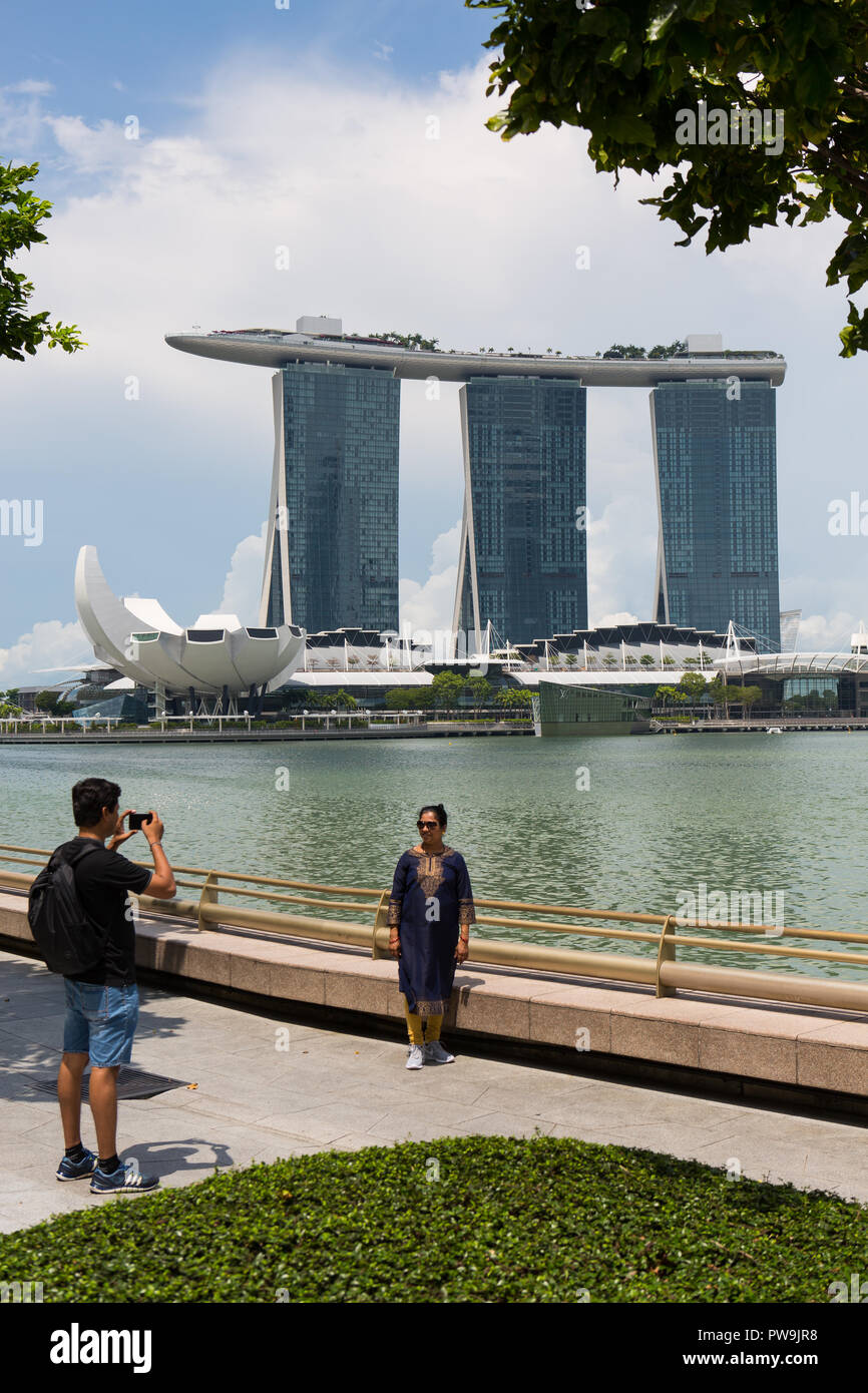 Donna turistica indiana verticale che posa per una foto presso l'iconica Marina Bay Sands. Luogo popolare per scattare immagini per la memoria. Singapore. Sud-est asiatico. Foto Stock