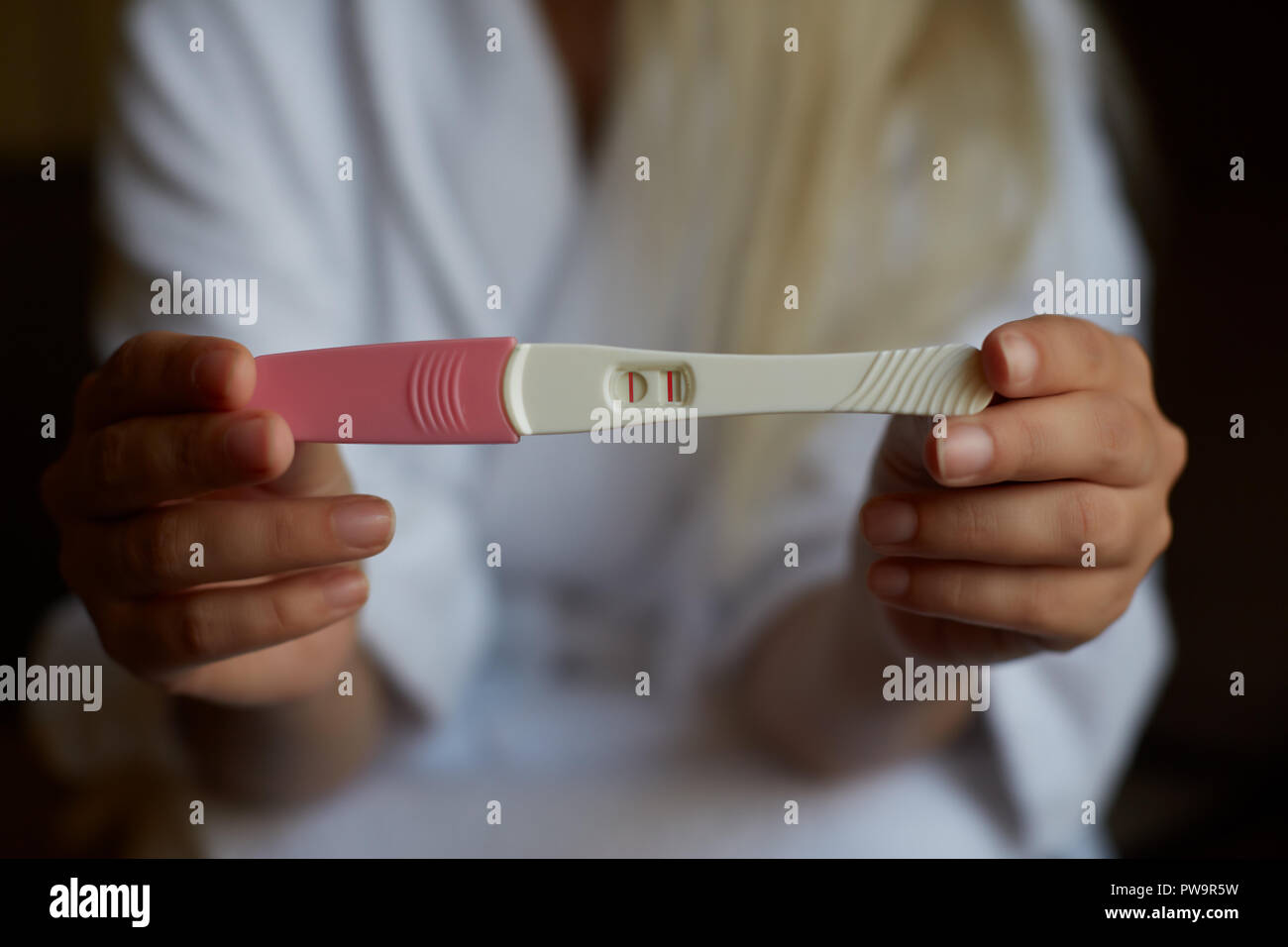 Close up donna mano che tiene una casa positivo al test di gravidanza. Foto Stock