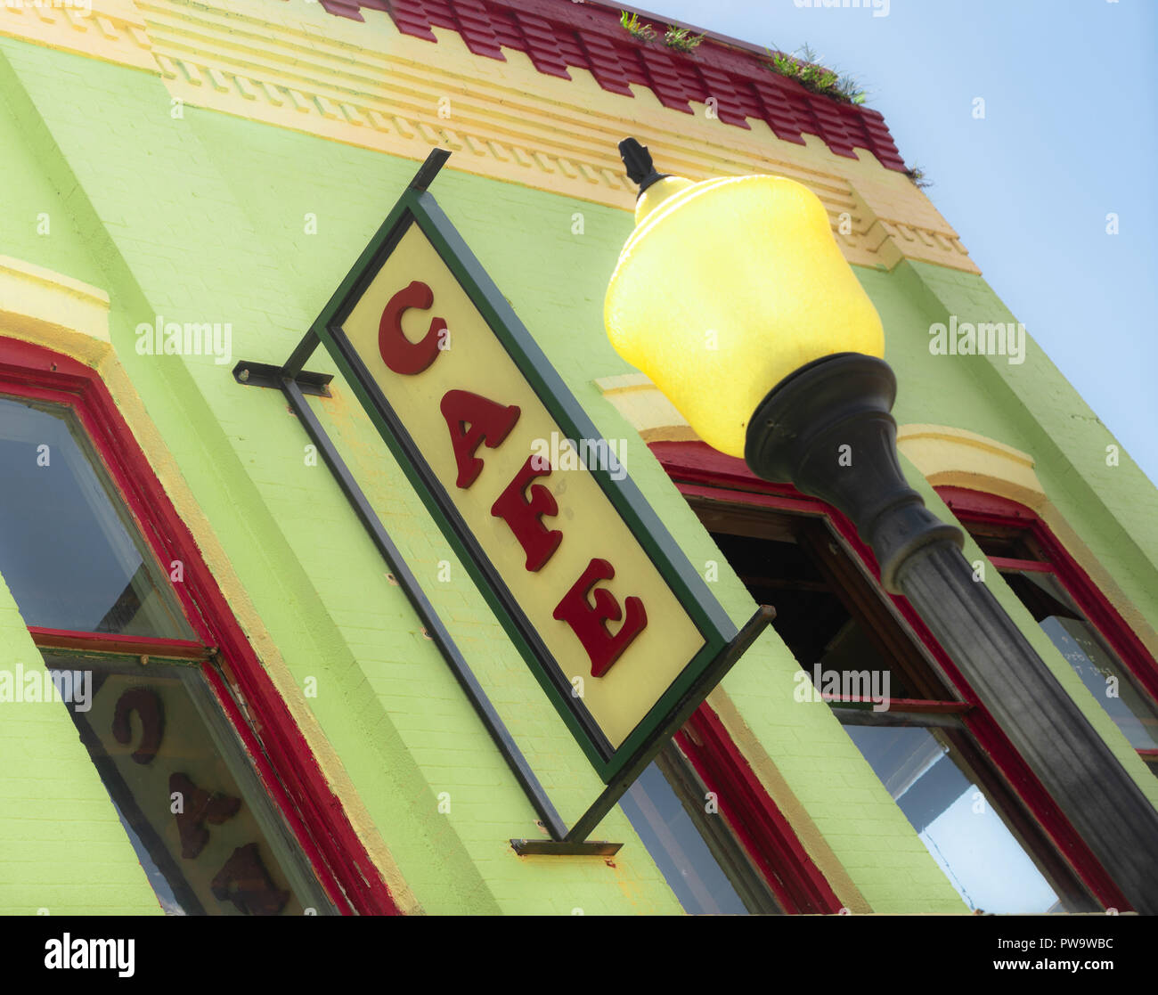 Raccolto a tenuta con il cielo blu e nuvole parete edilizia cafe segno vista inclinata lampione giallo Foto Stock
