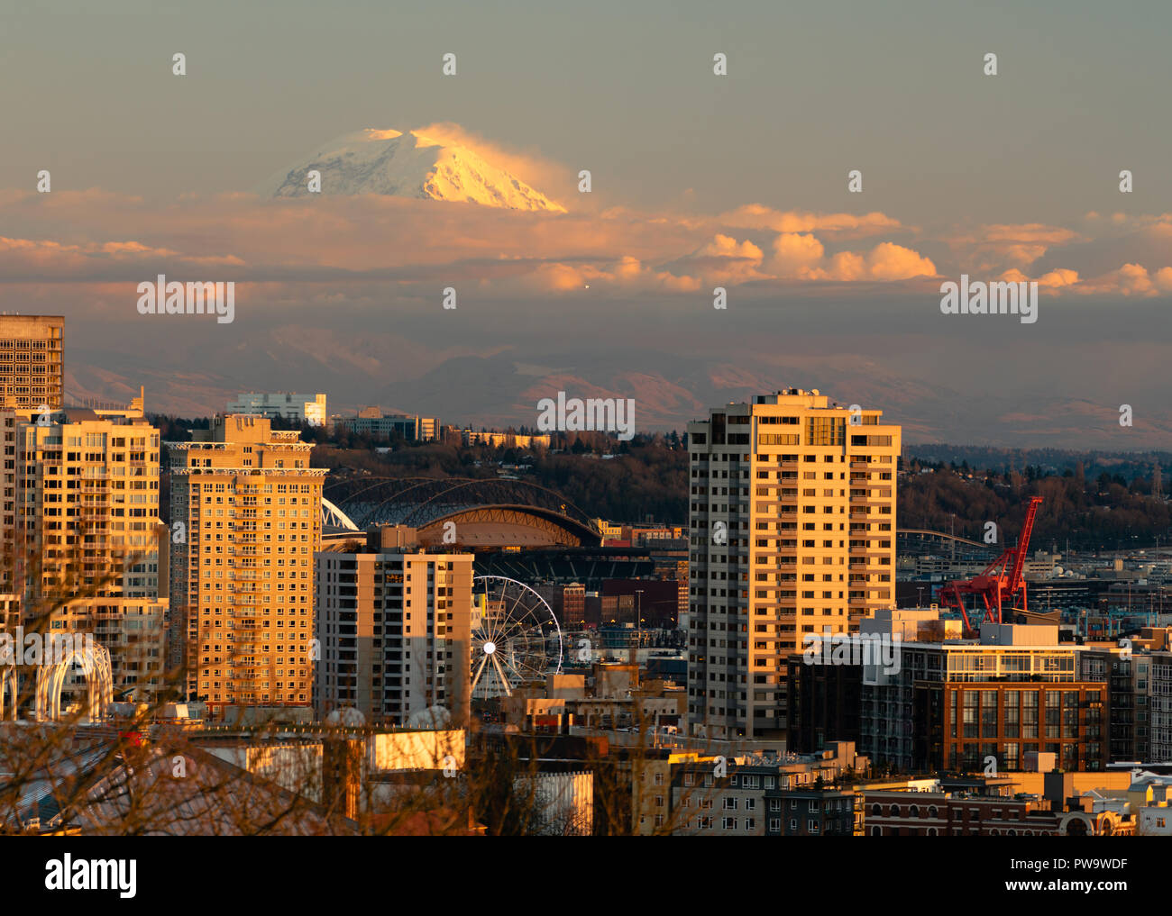 Le nuvole consentire alla sommità del monte Rainier per mostrare e ad incandescenza nella distanza dietro una porzione di Seattle Washington Foto Stock