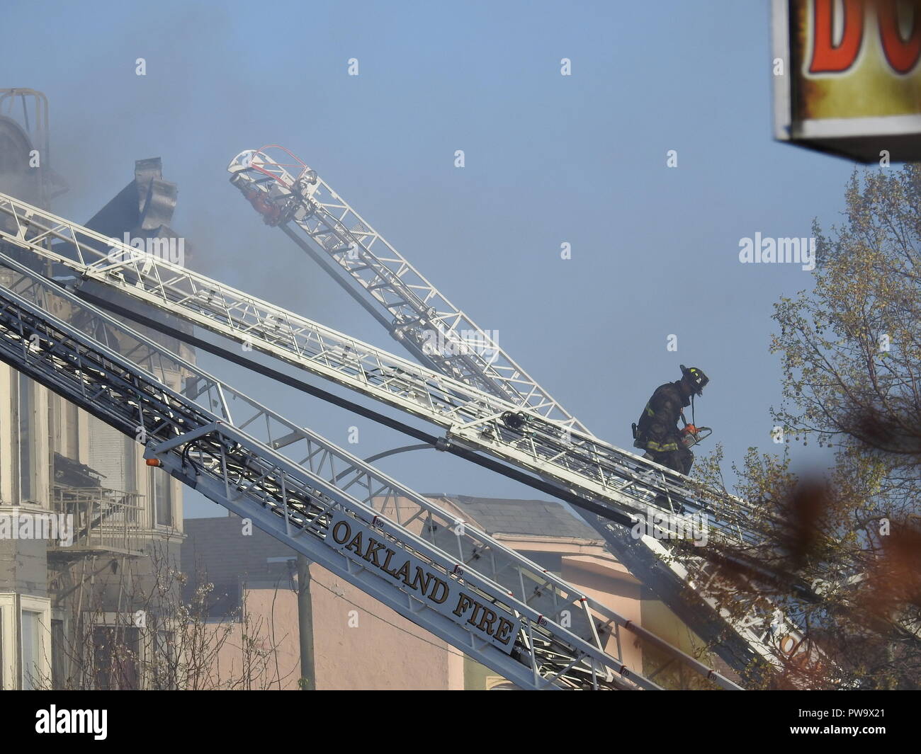 Un pompiere sale una scala mentre combatte un fuoco mortale in una casa a metà strada a San Pablo Ave. 2551 a Oakland il 27 marzo 2017. Foto Stock