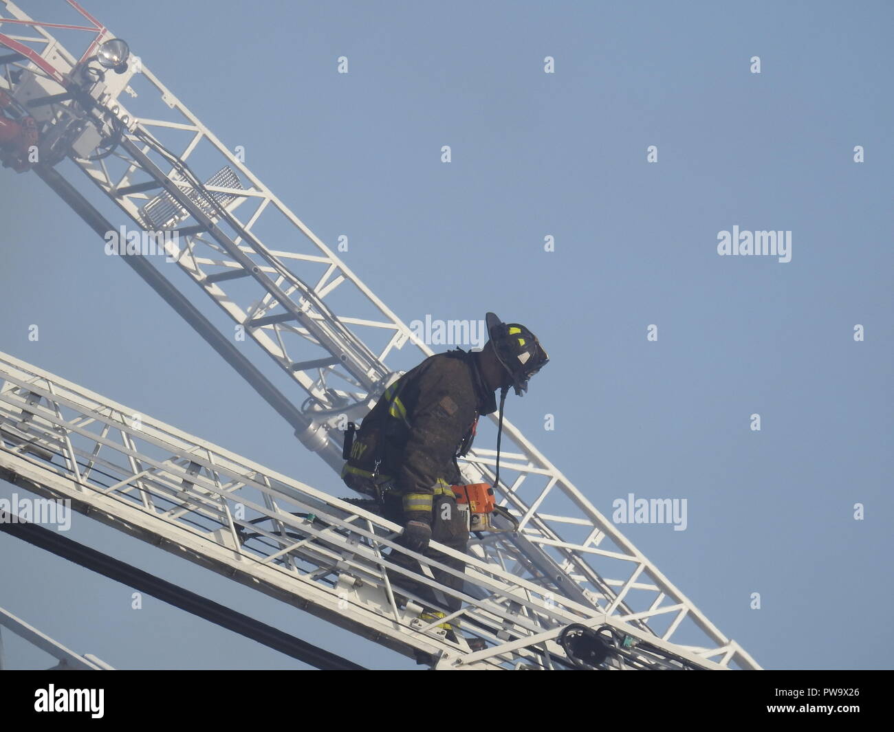 Un pompiere sale una scala mentre combatte un fuoco mortale in una casa a metà strada a San Pablo Ave. 2551 a Oakland il 27 marzo 2017. Foto Stock