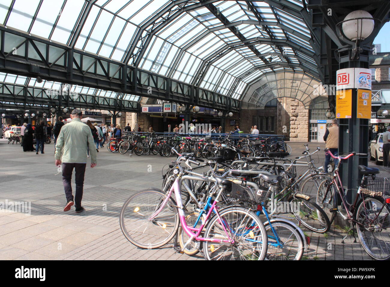 Uomo che cammina lontano da le biciclette parcheggiate sotto un tetto a cupola in vetro a Berlino, Germania Foto Stock