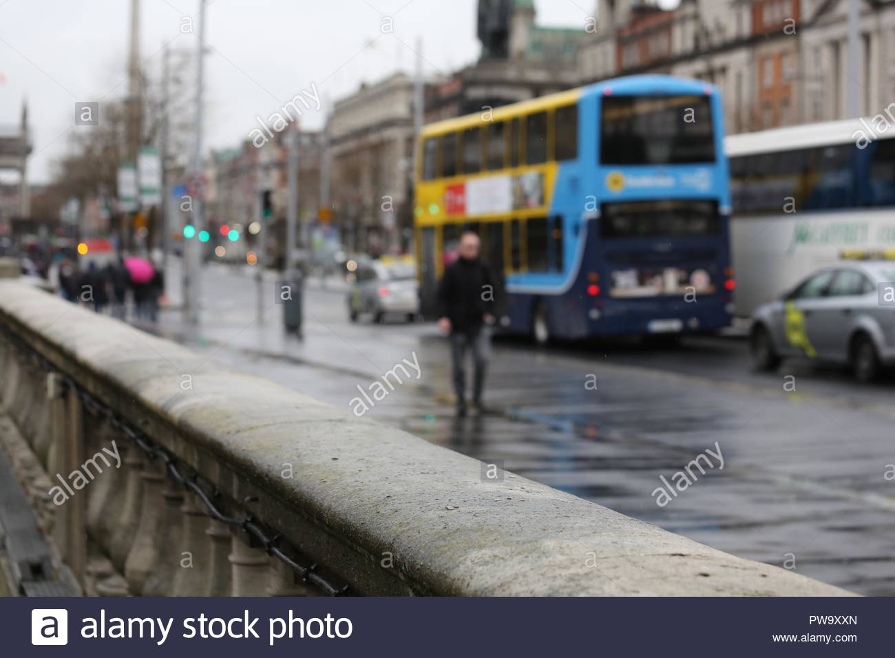 Le persone e gli autobus su O'Connell Bridge a Dublino, in Irlanda, in un giorno di pioggia nel mese di aprile Foto Stock