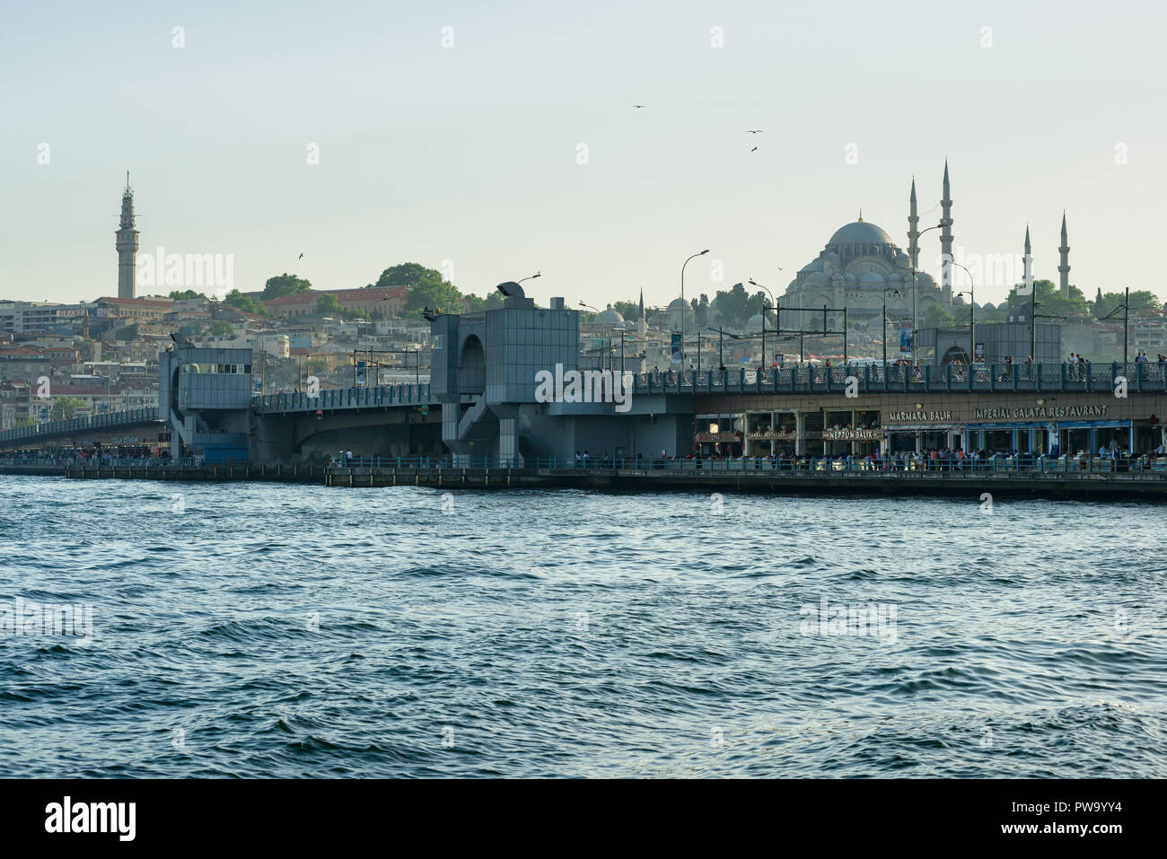 Il Ponte di Galata con ristoranti e la gente su di essa e la moschea di Suleymaniye in background, Istanbul, Turchia Foto Stock