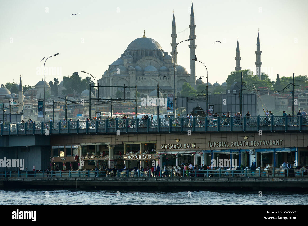 Il Ponte di Galata con ristoranti e la gente su di essa e la moschea di Suleymaniye in background, Istanbul, Turchia Foto Stock
