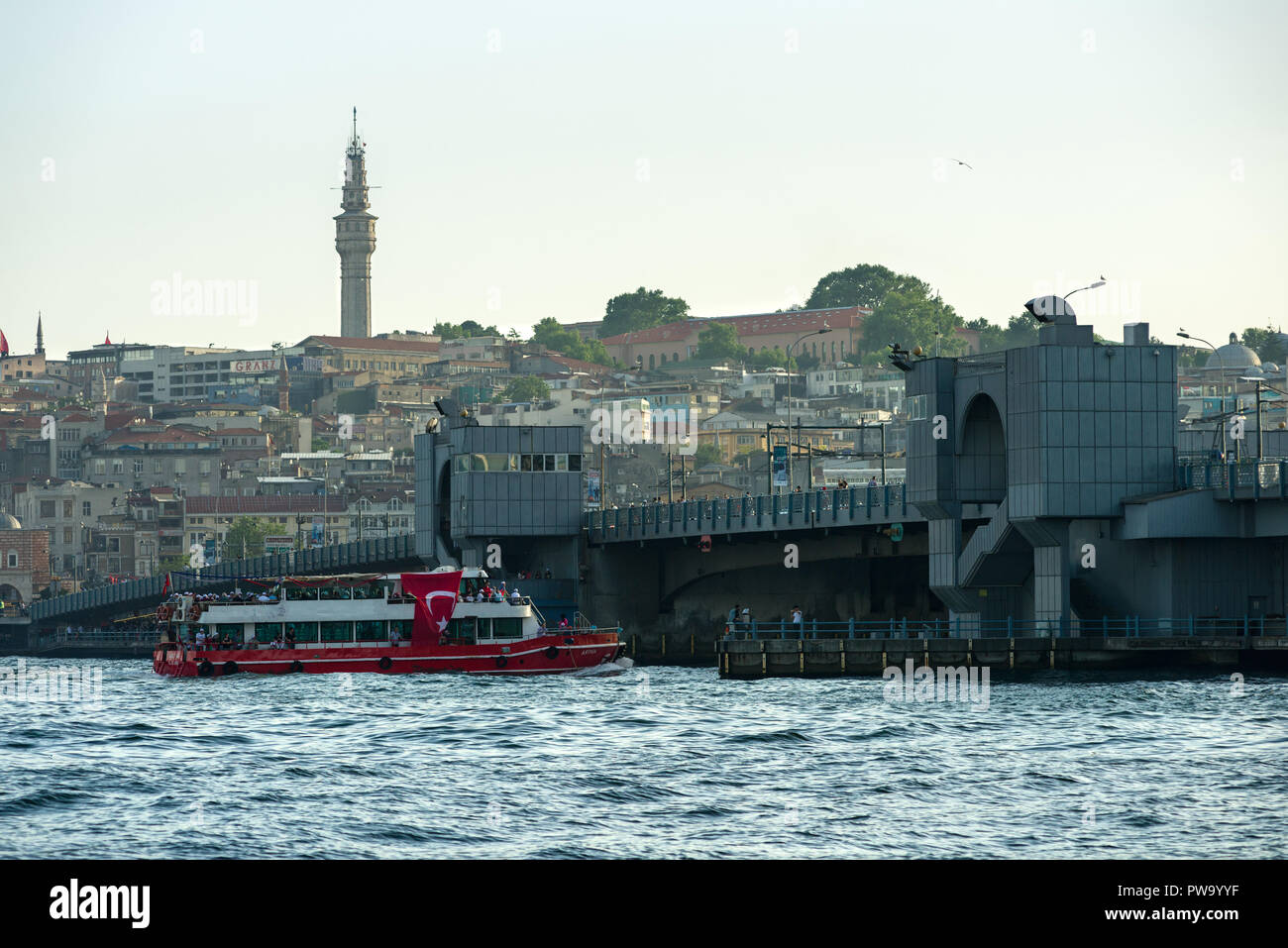Un rosso e bianco traghetto con una grande bandiera turca su di esso la vela sotto il ponte Galata, Istanbul, Turchia Foto Stock