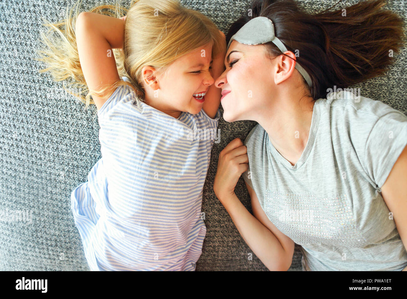Tenere premuto è stretto. Carino amorevole donna emotiva abbracciando la figlia stretto mentre la spesa la mattina a letto e sentirsi felice. Il naso a naso Foto Stock