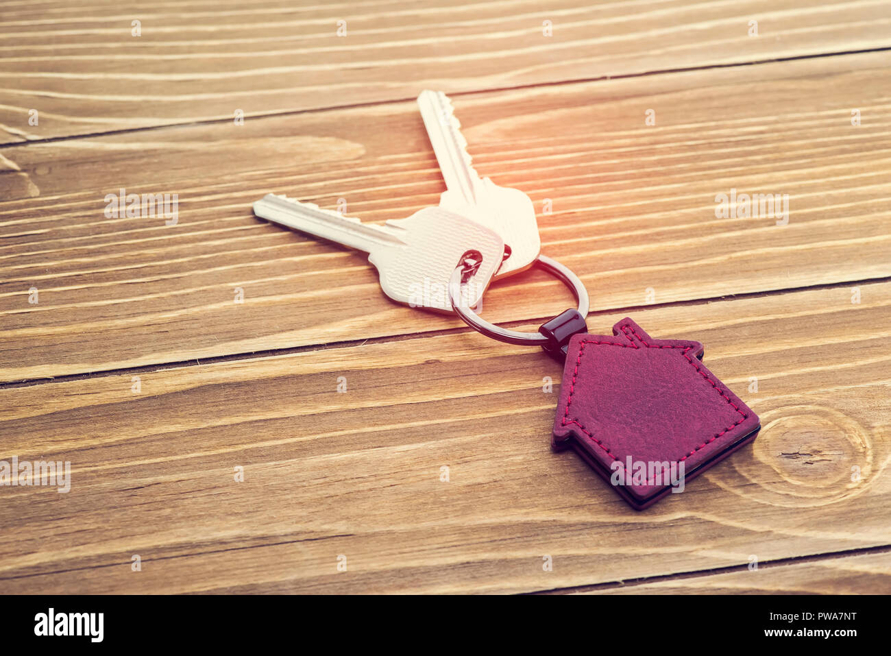 Catena della chiave con il simbolo della casa e le chiavi su sfondo di legno,immobiliare di concetto Foto Stock