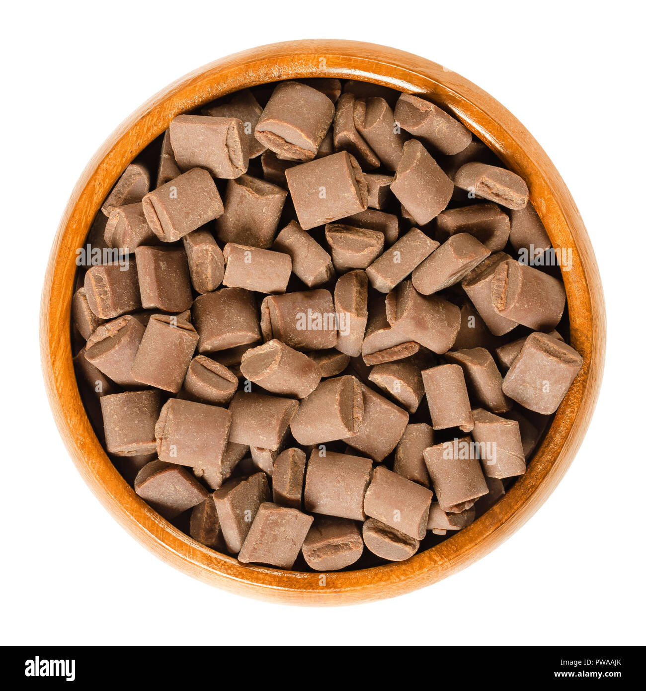 Aggiungete pezzetti di cioccolato in tazza di legno. Il cioccolato al latte di pezzi per la cottura e la decorazione di biscotti, focaccine e coccinelle. Commestibile igredient cottura. Foto Stock