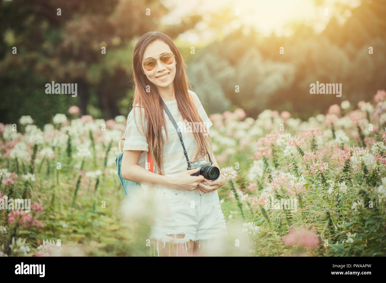 Ragazza asiatica rilassarsi godersi la vacanza con la fotografia fiore hobby nel parco vintage tono colore Foto Stock