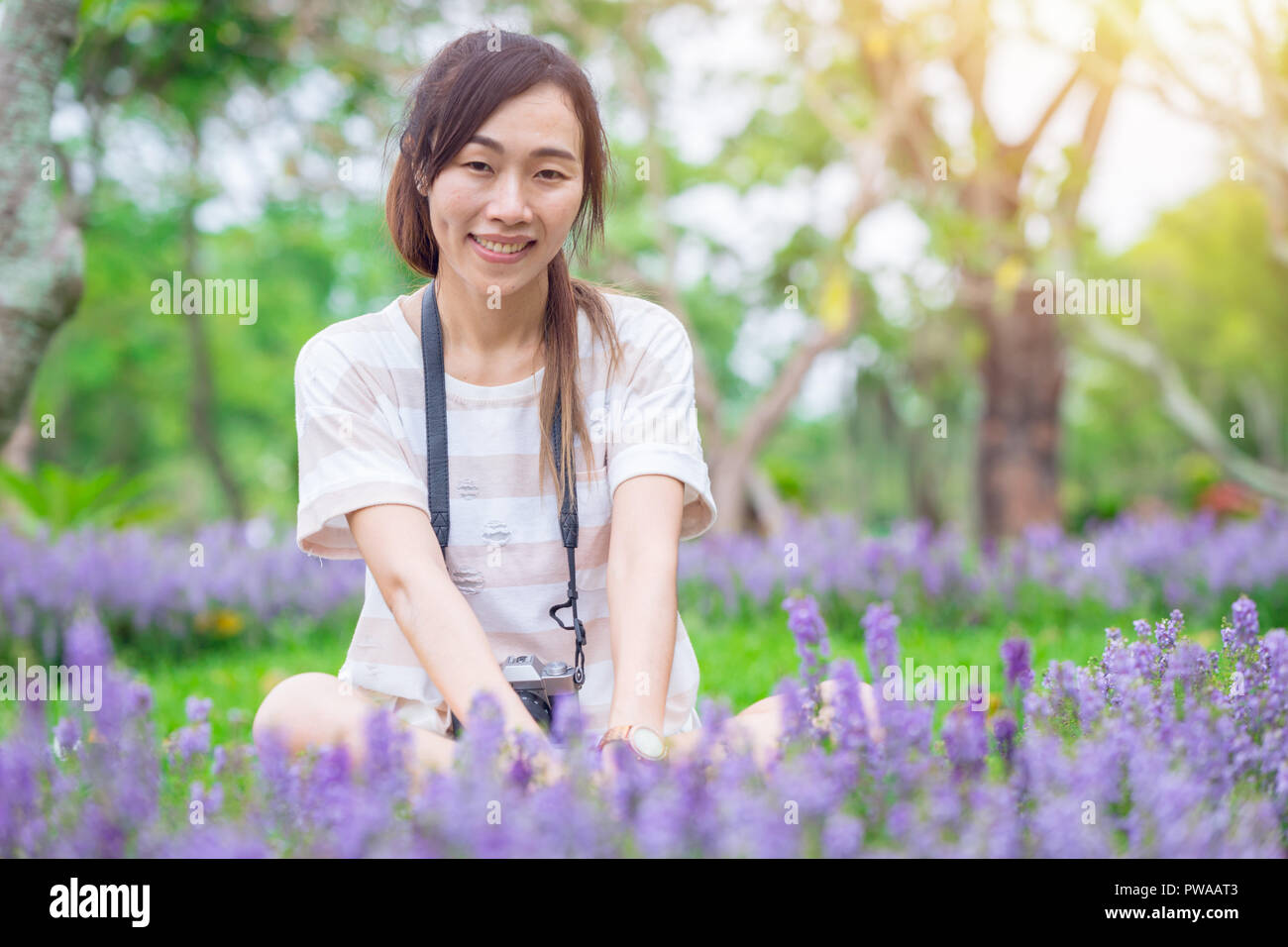 Ragazza asiatica rilassarsi godersi la vacanza con la fotografia fiore hobby nel parco Foto Stock