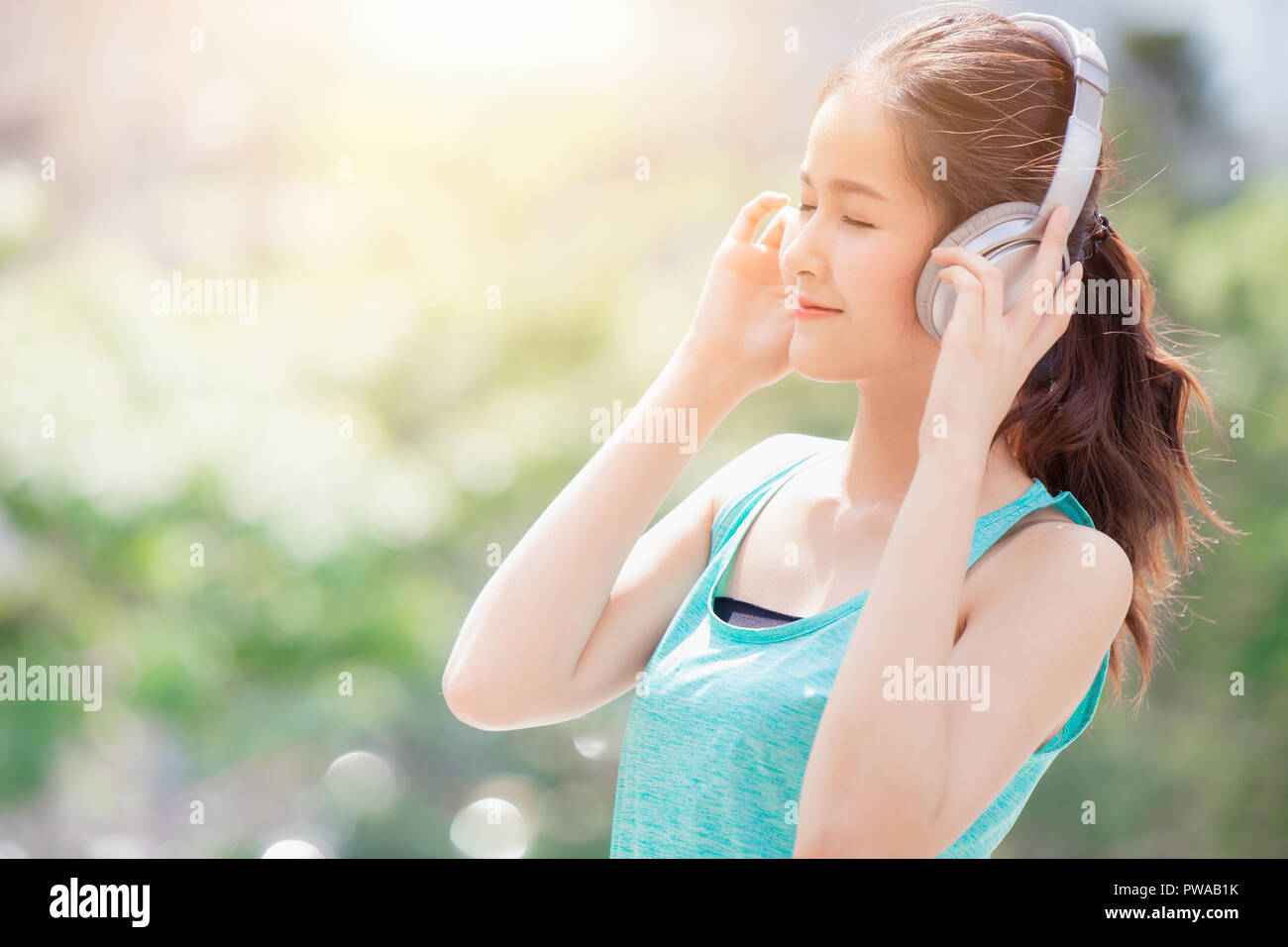 Asiatica bella carino teen ascolto di musica con cuffie wireless sport abito sano godere sorridente Foto Stock