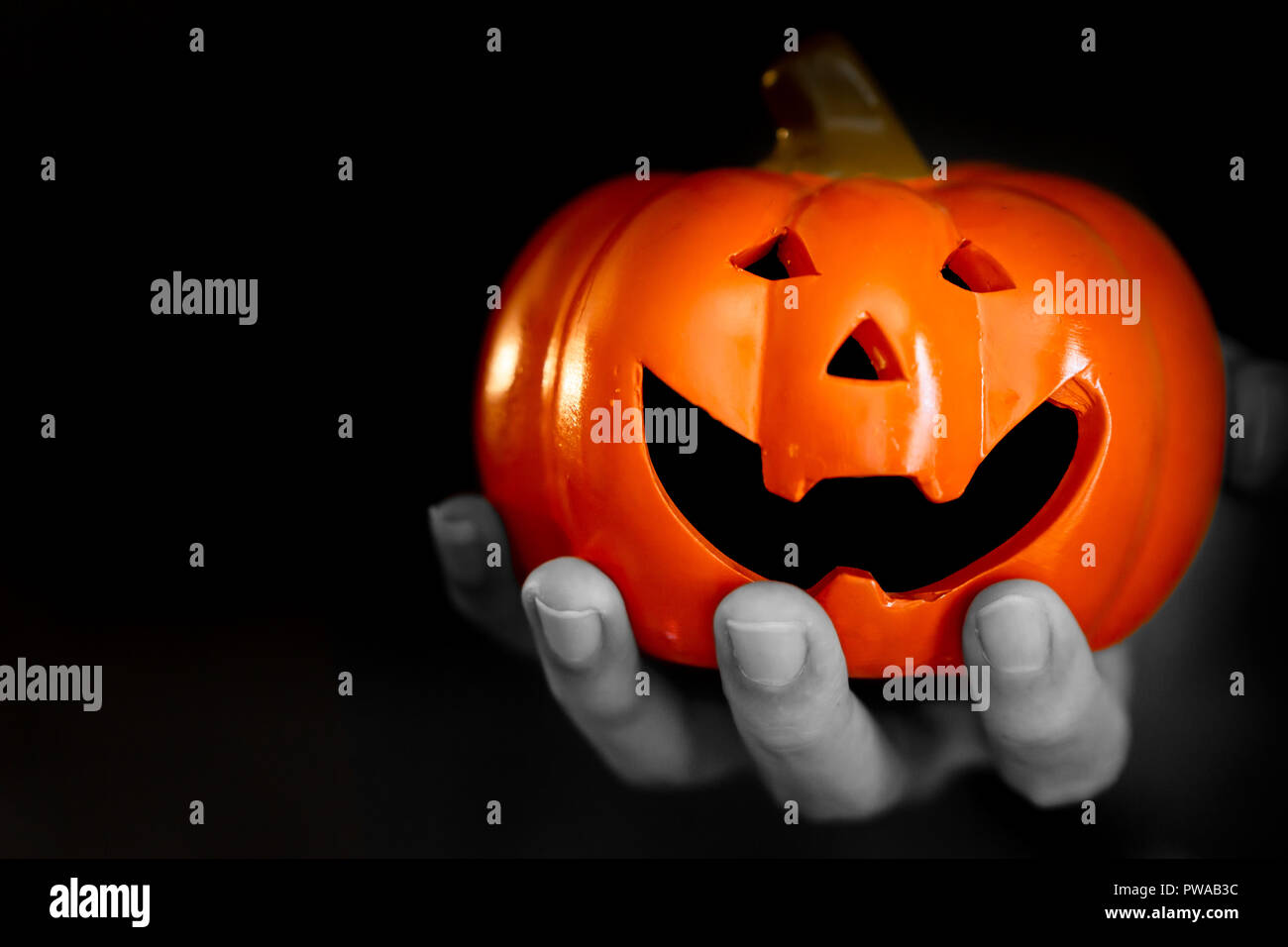 Mano di zombie con helloween sorriso incubo di zucca dolcetto o scherzetto festa su sfondo nero Foto Stock