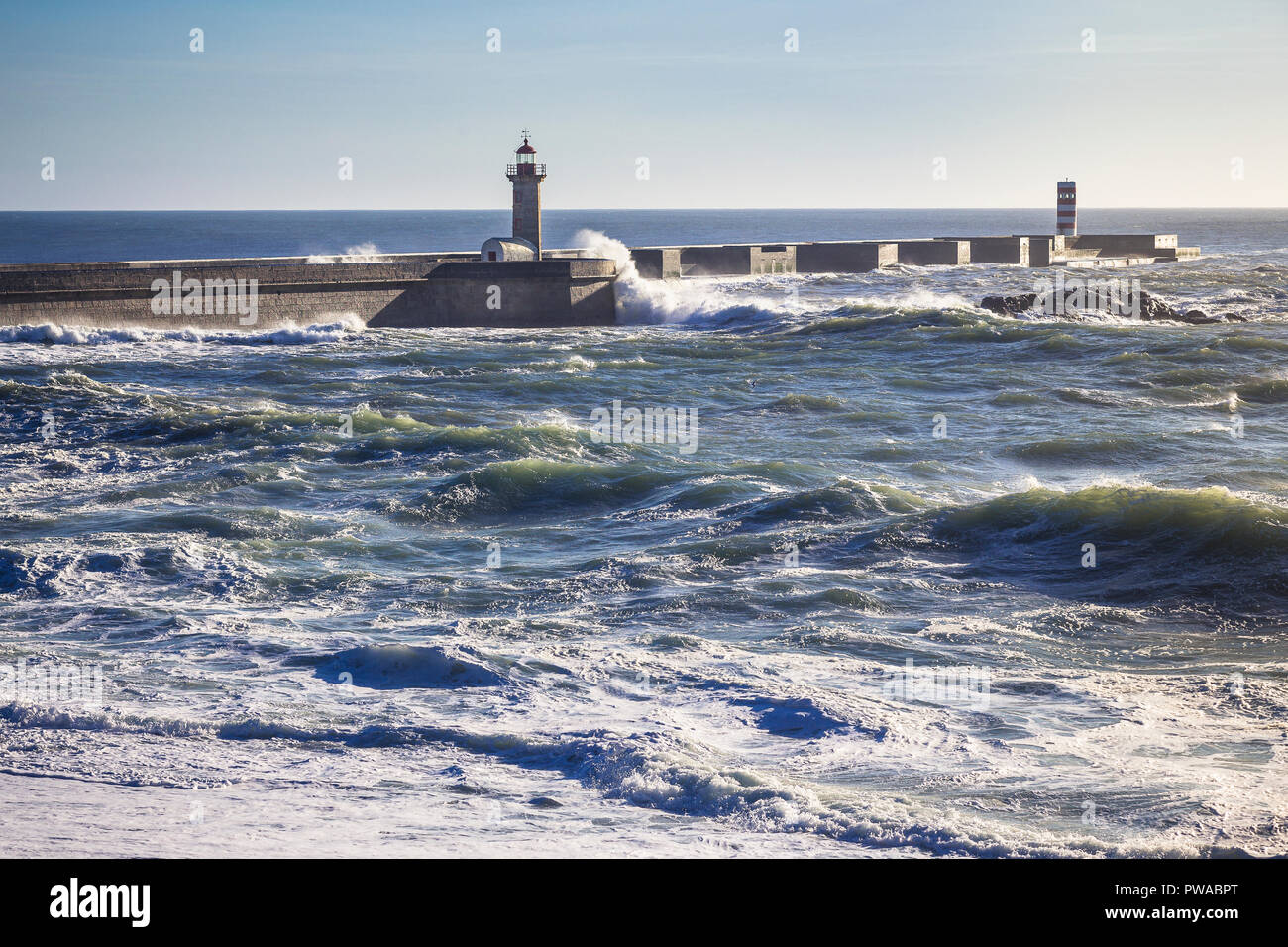 Onde di una ruvida Atlantic schiantarsi sul Porto è pier con Farolim de Felgueiras Faro, Portogallo Foto Stock