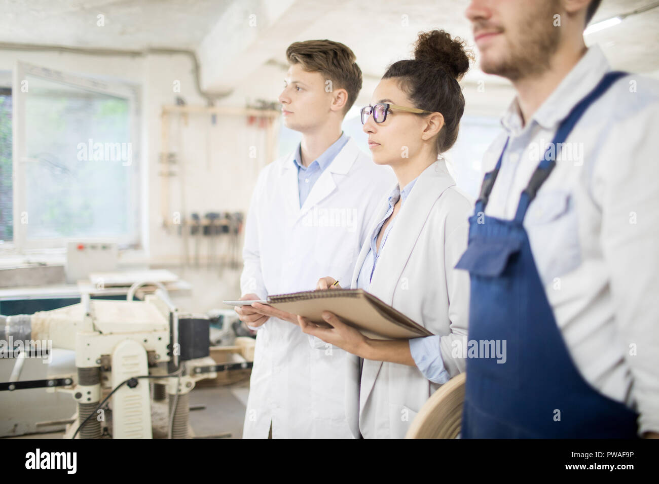 Fila di giovani studenti di whitecoats rendendo note alla lezione in officina Foto Stock