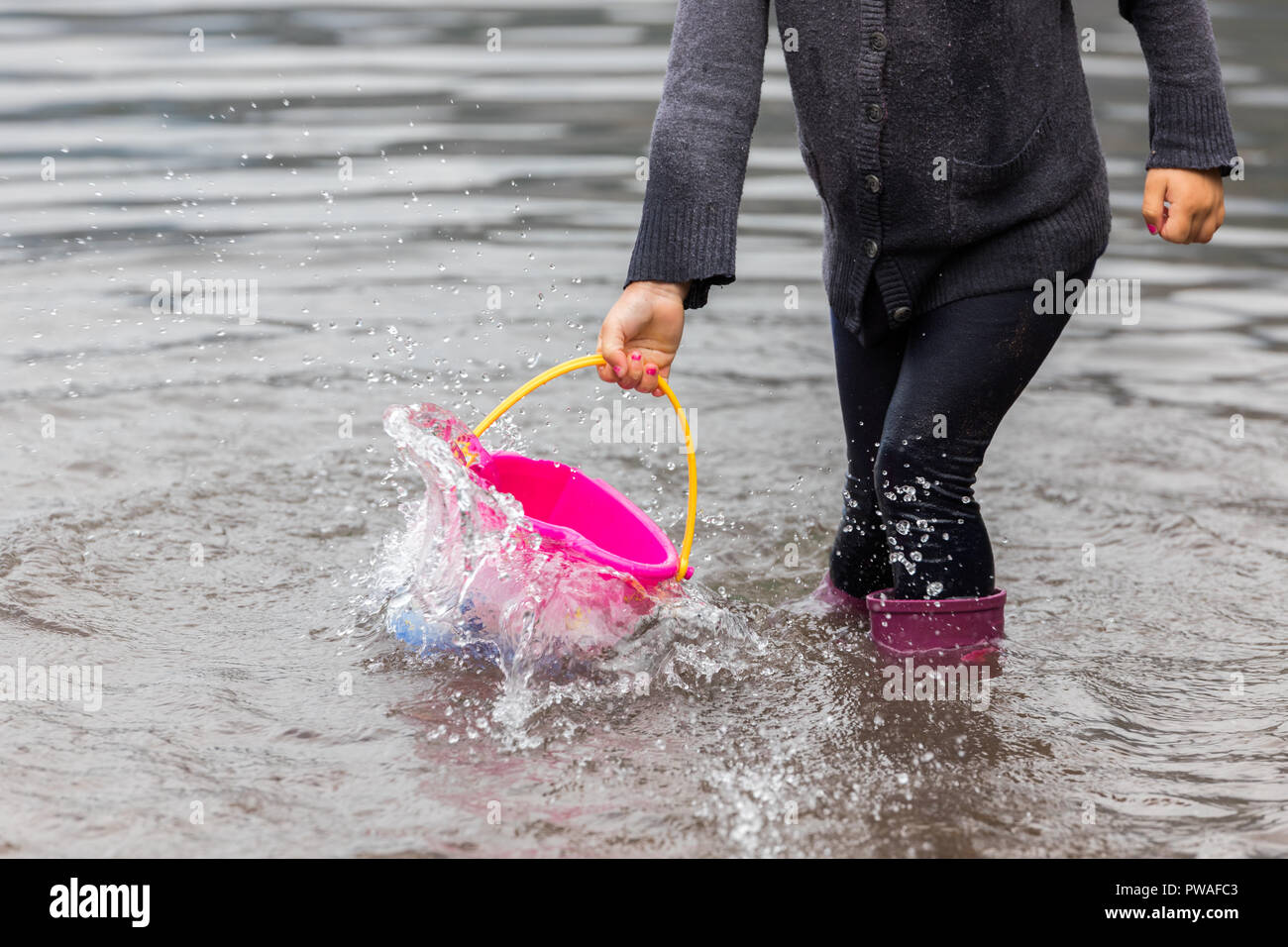 Bambini che giocano in un lago con un secchio in il Walensee, diventando completamente bagnati nel processo. Foto Stock