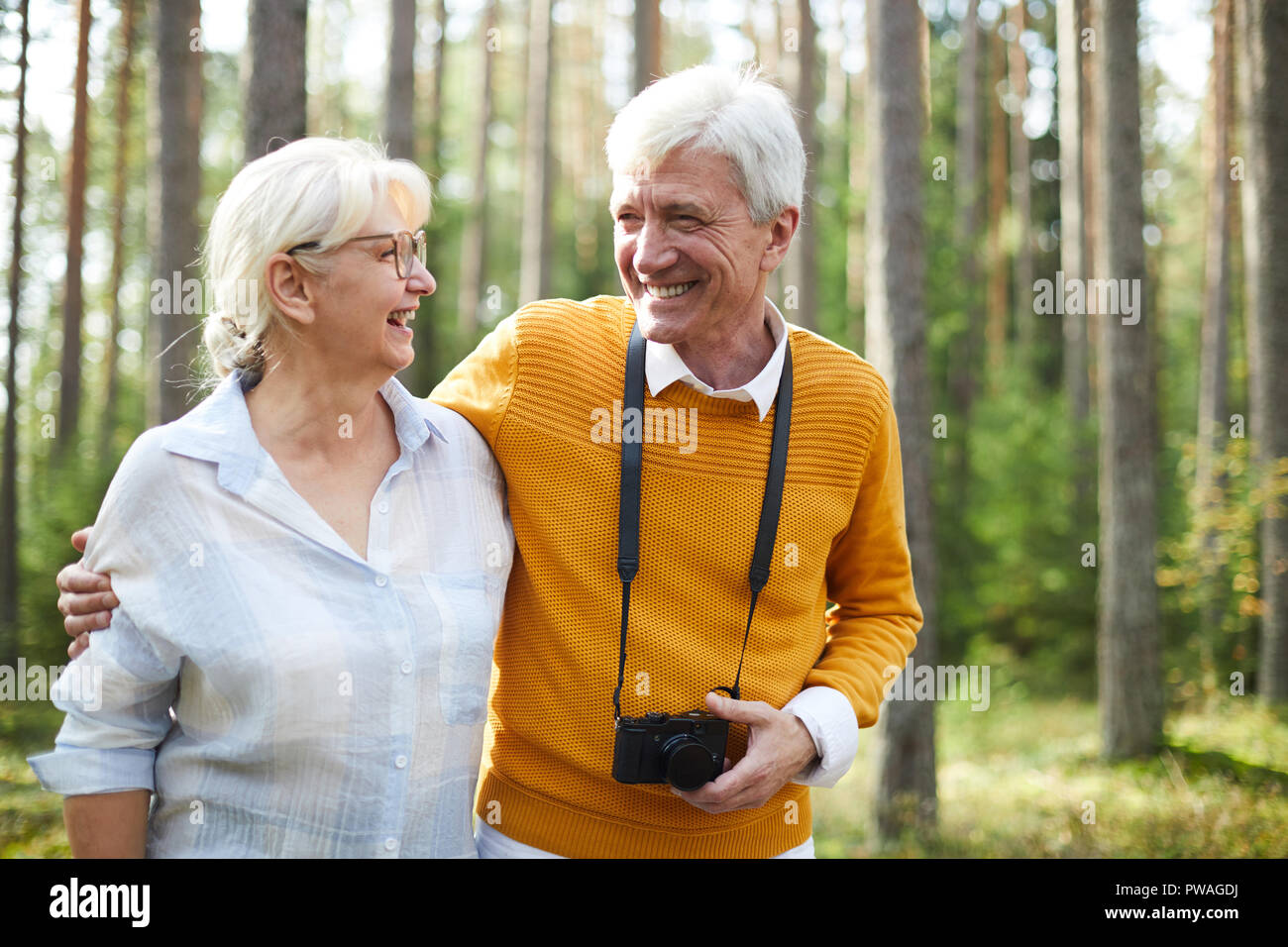 Gioiosa affettuosa coppia senior di refrigerazione nella foresta sul giorno di estate, di parlare e di fotografare la natura Foto Stock