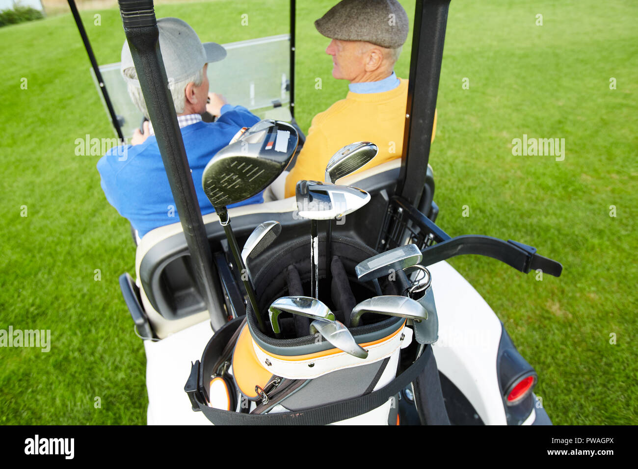 Vista posteriore del golf car con mazzetto di mazze da golf e due uomini maturi parlando in cabina Foto Stock