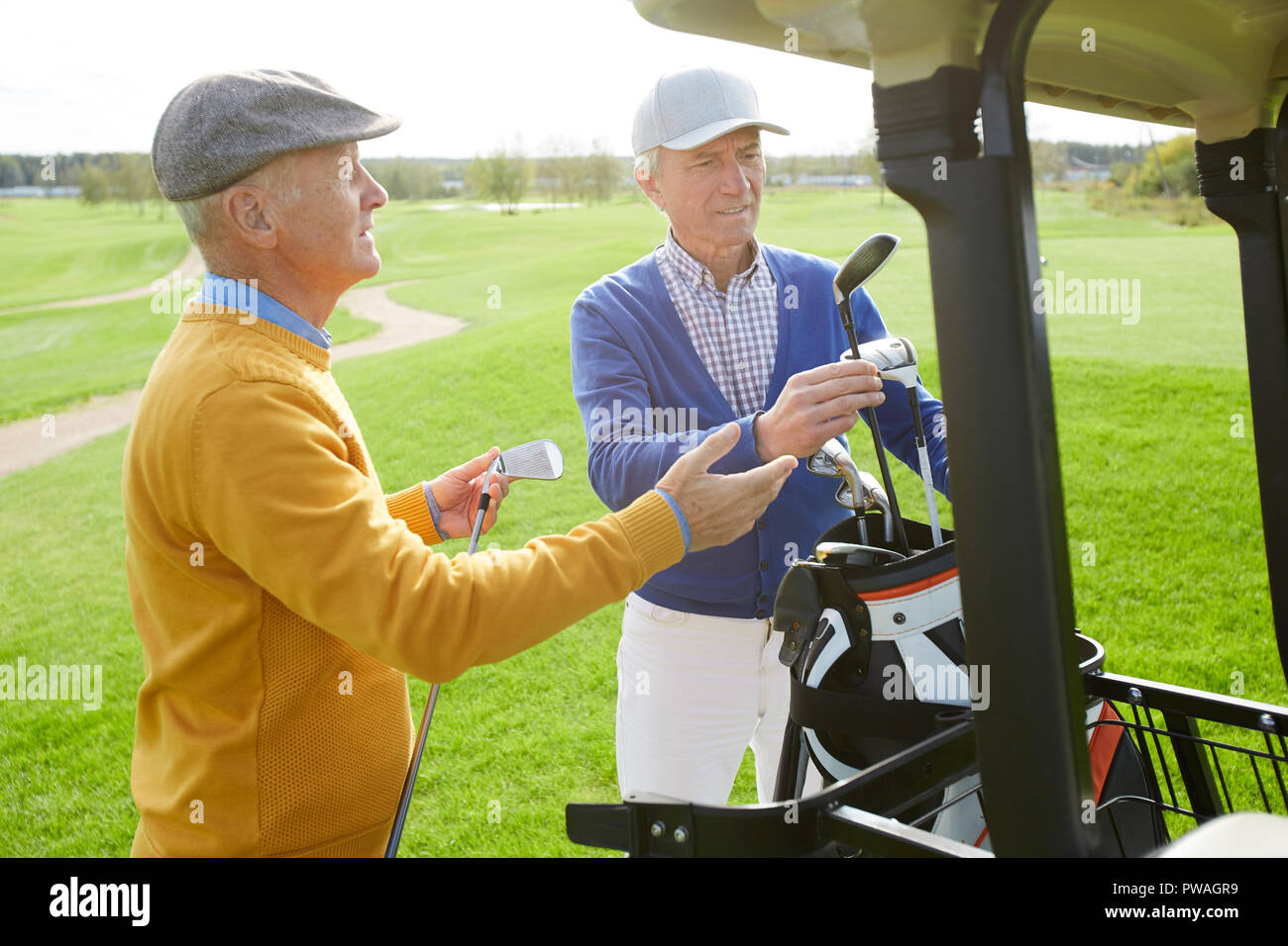 Due gentili uomini maturi la scelta di mazze da golf mentre andando a giocare il gioco all'aperto a piacere Foto Stock
