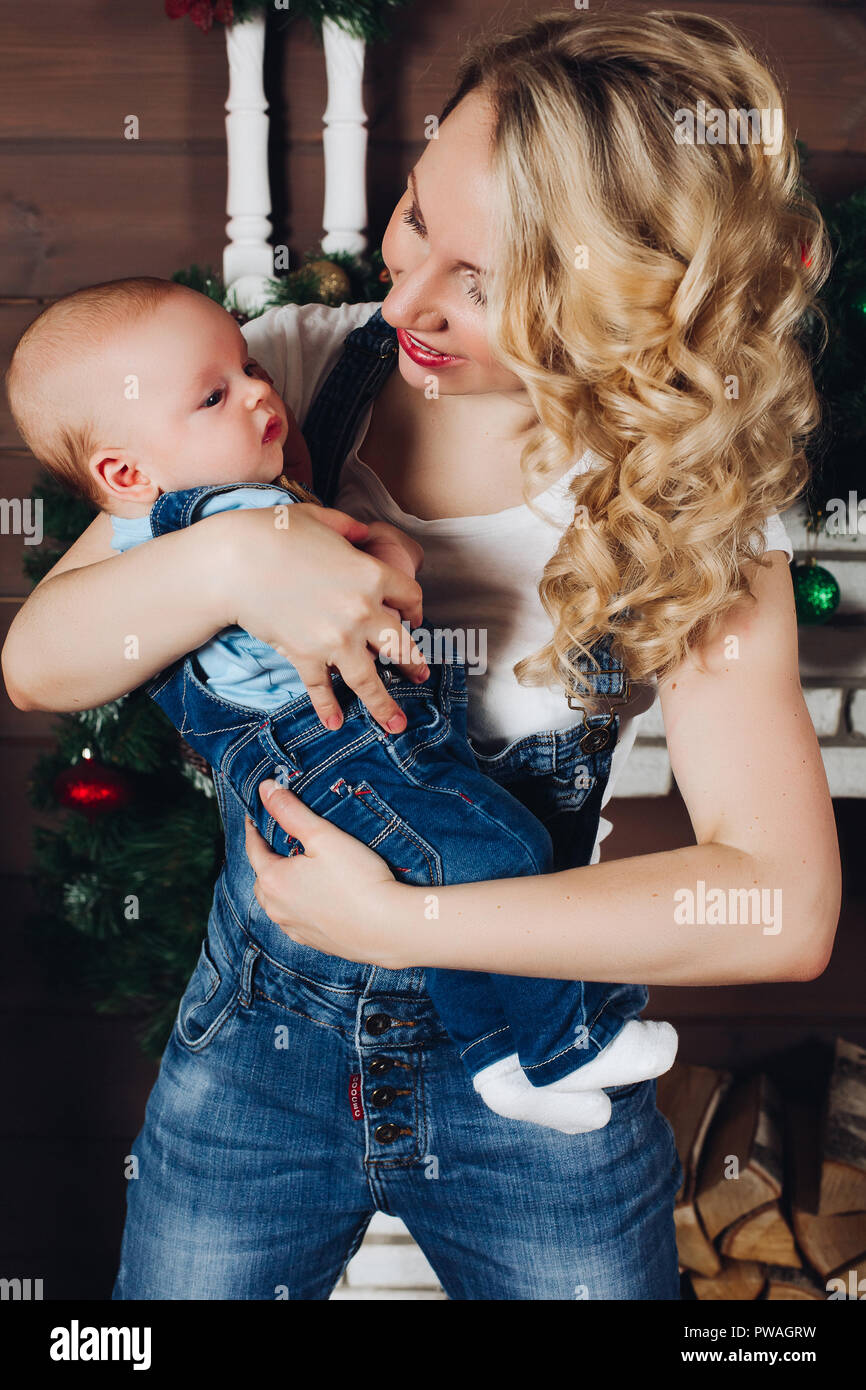 Ragazzo con la bella bionda mom abbracciando in studio decorato per il Natale. Foto Stock