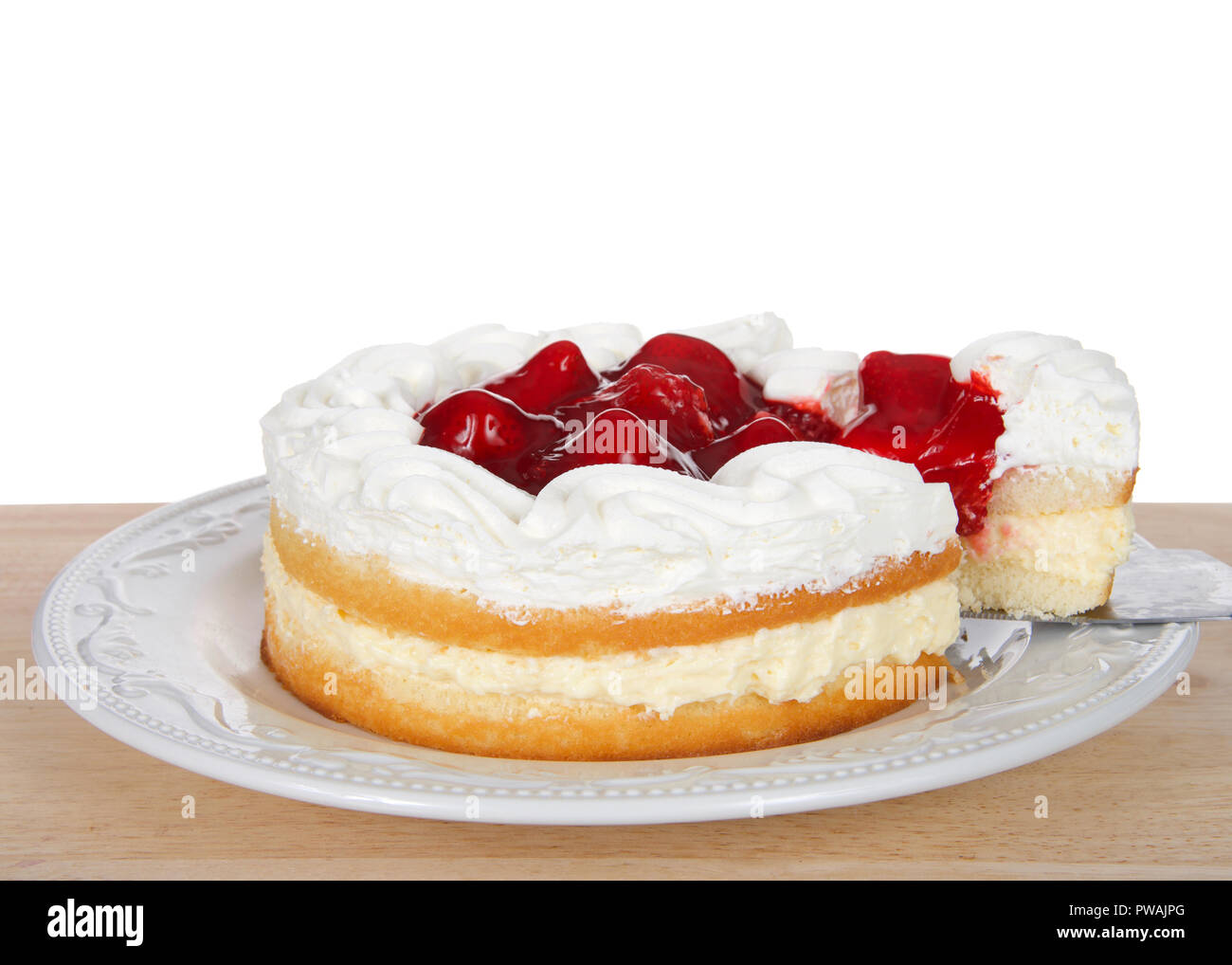 Fragola breve torta con crema di farcitura sulla piastra bianca, panna montata e fragole in cima. Slice è tirato fuori della torta. Sulla tavola di legno isolato Foto Stock