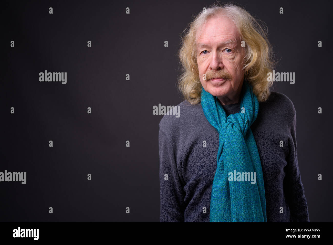 Senior uomo con i baffi contro uno sfondo grigio Foto Stock