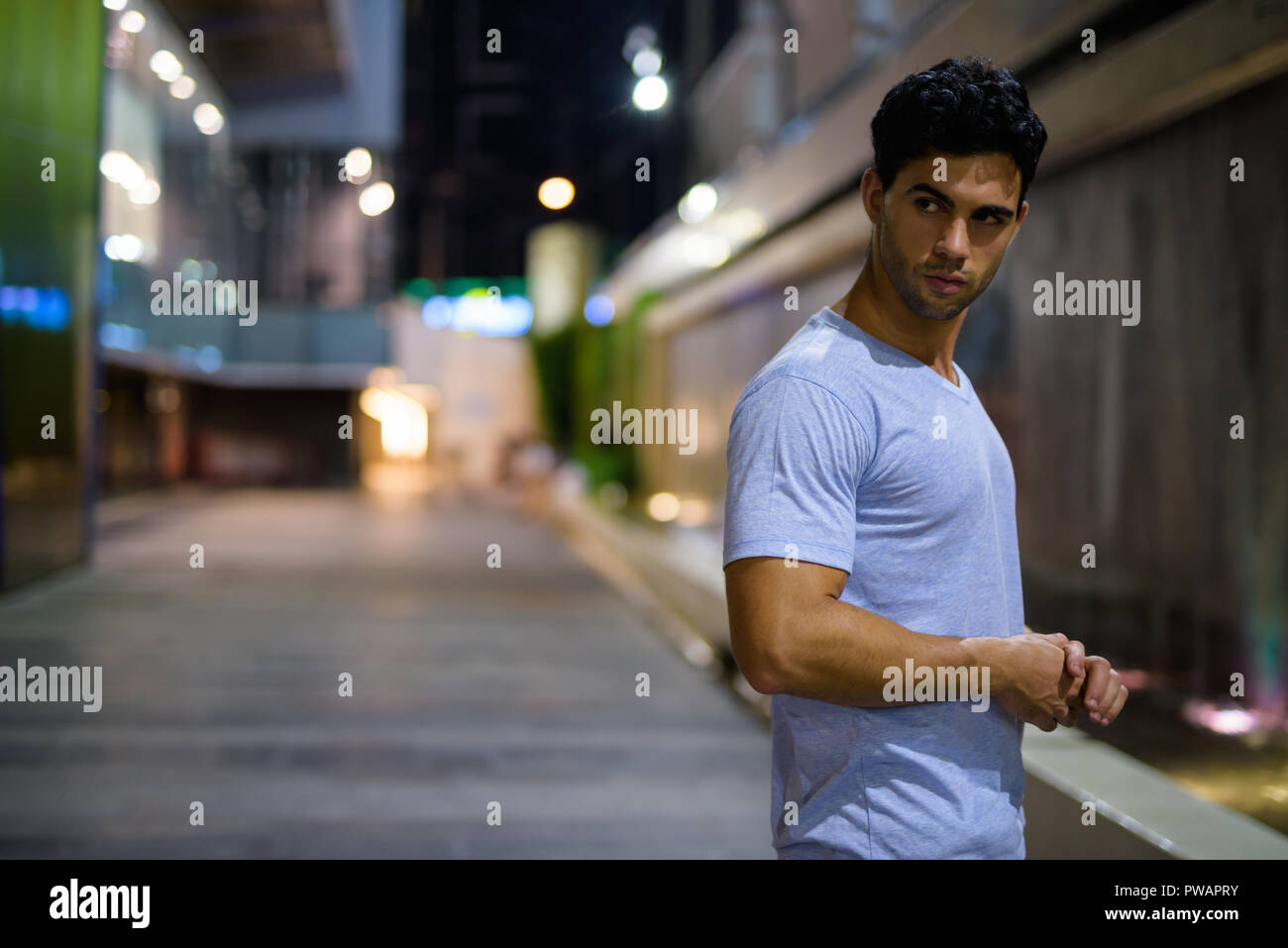 Bel giovane uomo ispanico ad esplorare le strade della città di notte Foto Stock