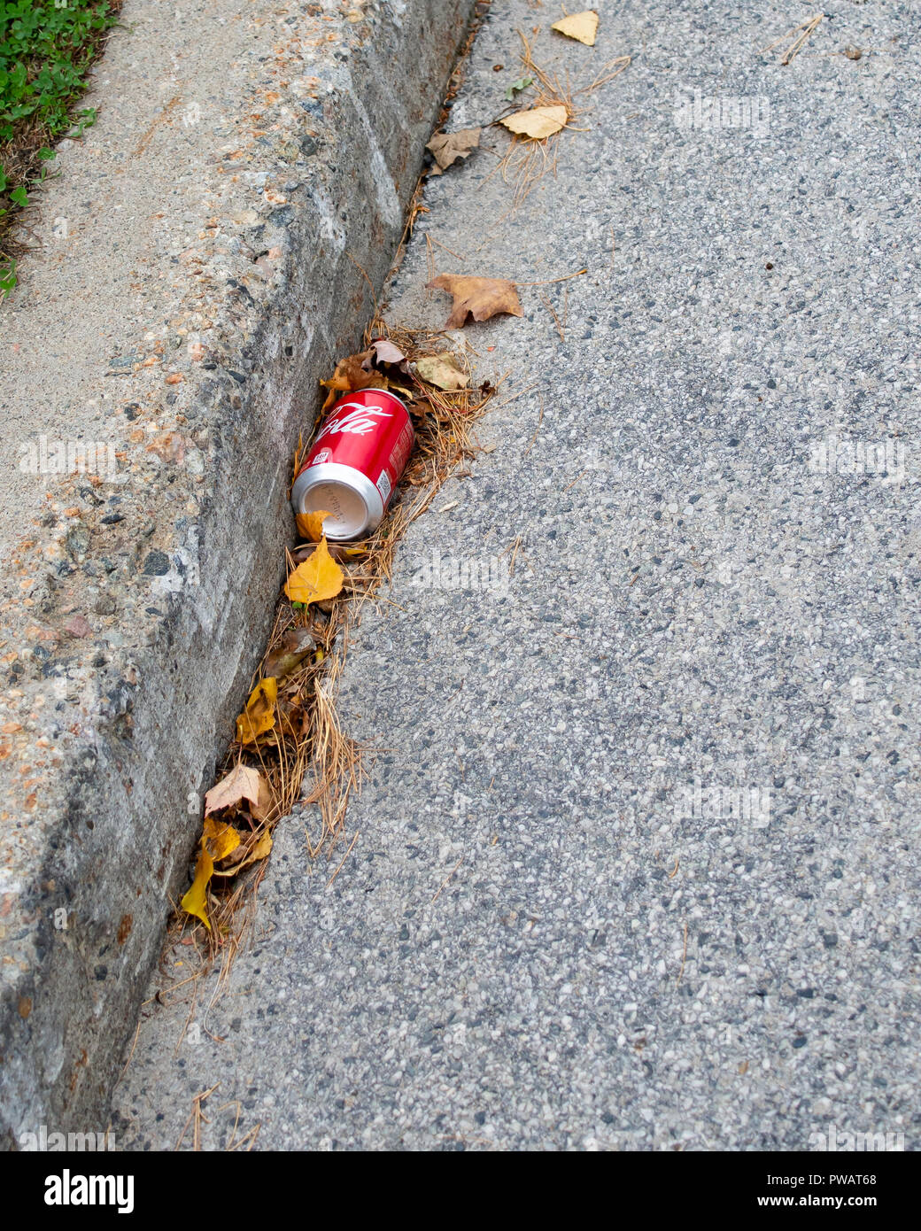 Un vuoto scartato Coke può giacenti in strada o grondaia in speculatore, NY USA, concetto di lettiera. Foto Stock