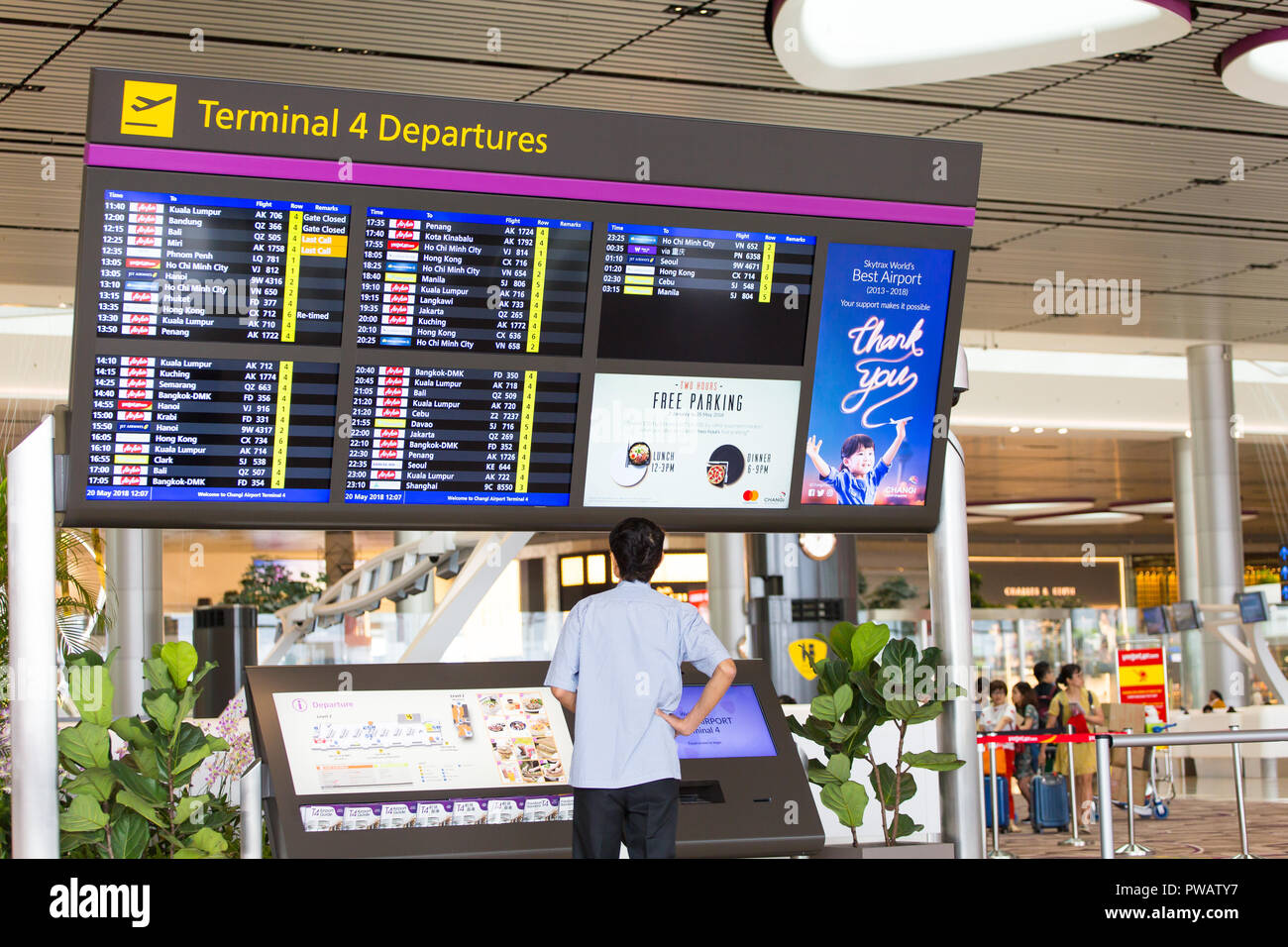 Man controlla l'orario di partenza del sistema di visualizzazione delle informazioni sui voli delle compagnie aeree Changi Airport Terminal 4. Il T4 è l'aeroporto più recente, aperto nel 2018. Foto Stock