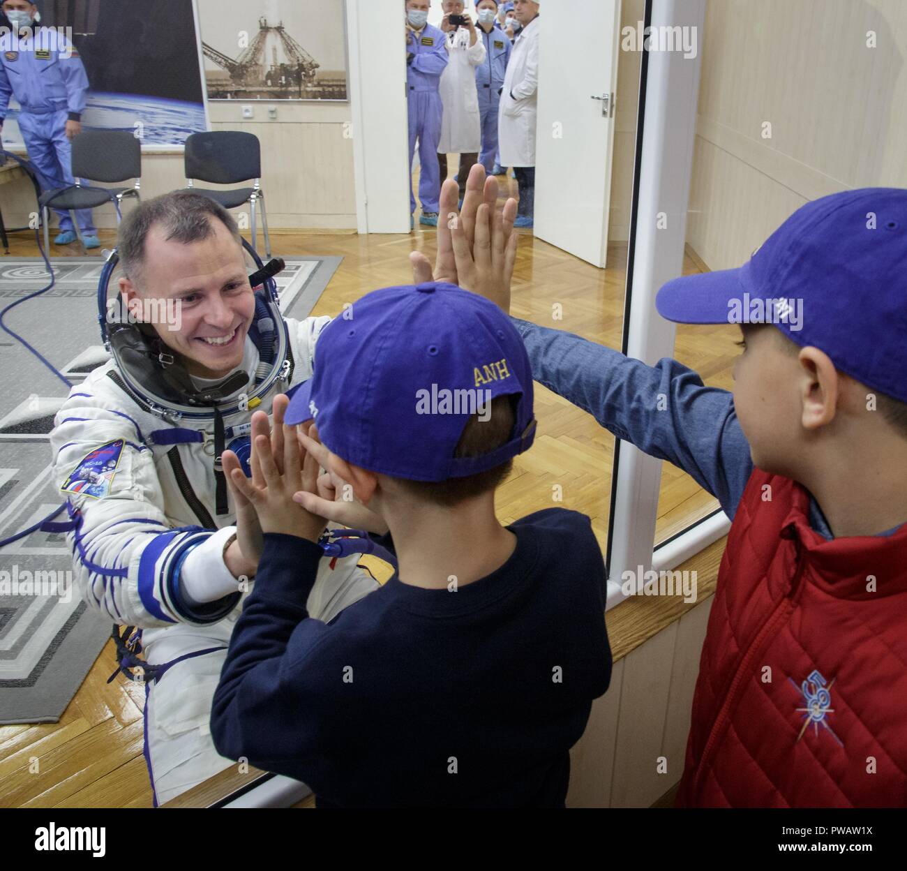 Expedition 57 Tecnico di volo Nick aia della NASA dice addio ai suoi figli dopo la sua tuta Sokol controllato di pressione prima del suo lancio su un razzo Soyuz con spedizione 57 Tecnico di volo Alexey Ovchinin di Roscosmos, presso il cosmodromo di Baikonur Ottobre 11, 2018 di Baikonur in Kazakhstan. Poco dopo il sollevare il malfunzionamento del razzo in rotta verso la stazione spaziale internazionale e interrotta la forzatura di un atterraggio di emergenza in Kazakistan. I membri di equipaggio sono stati prelevati da ricerca e soccorso e secondo come riferito sono in buone condizioni. Foto Stock