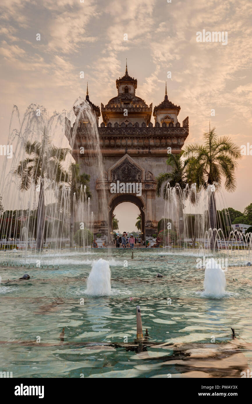 Fontana, palme e pochi turisti al Patuxai (Patuxay), vittoria gate o gate del trionfo, monumento di guerra in Vientiane, Laos, al tramonto. Foto Stock