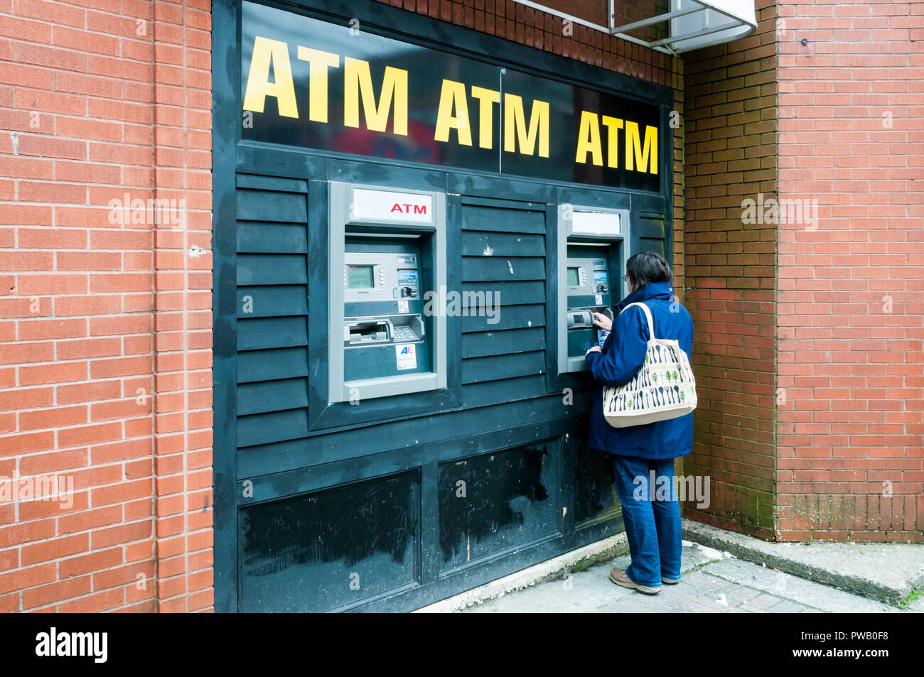 Una donna di prelevare denaro da un bancomat. Foto Stock