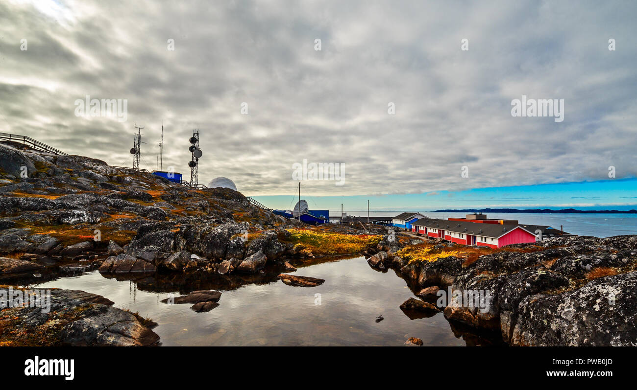 Rocce, lago, abitazioni e la torre della radio in background in un sobborgo della città di Nuuk, Groenlandia Foto Stock