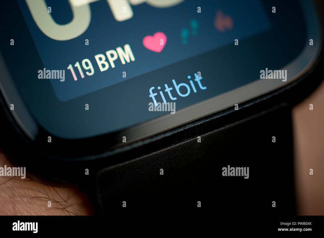 Un uomo controlla il suo Fitbit Versa il tracker di attività compresi monitor frequenza cardiaca utilizzando il BPM di unità durante un esercizio allenamento. Foto Stock