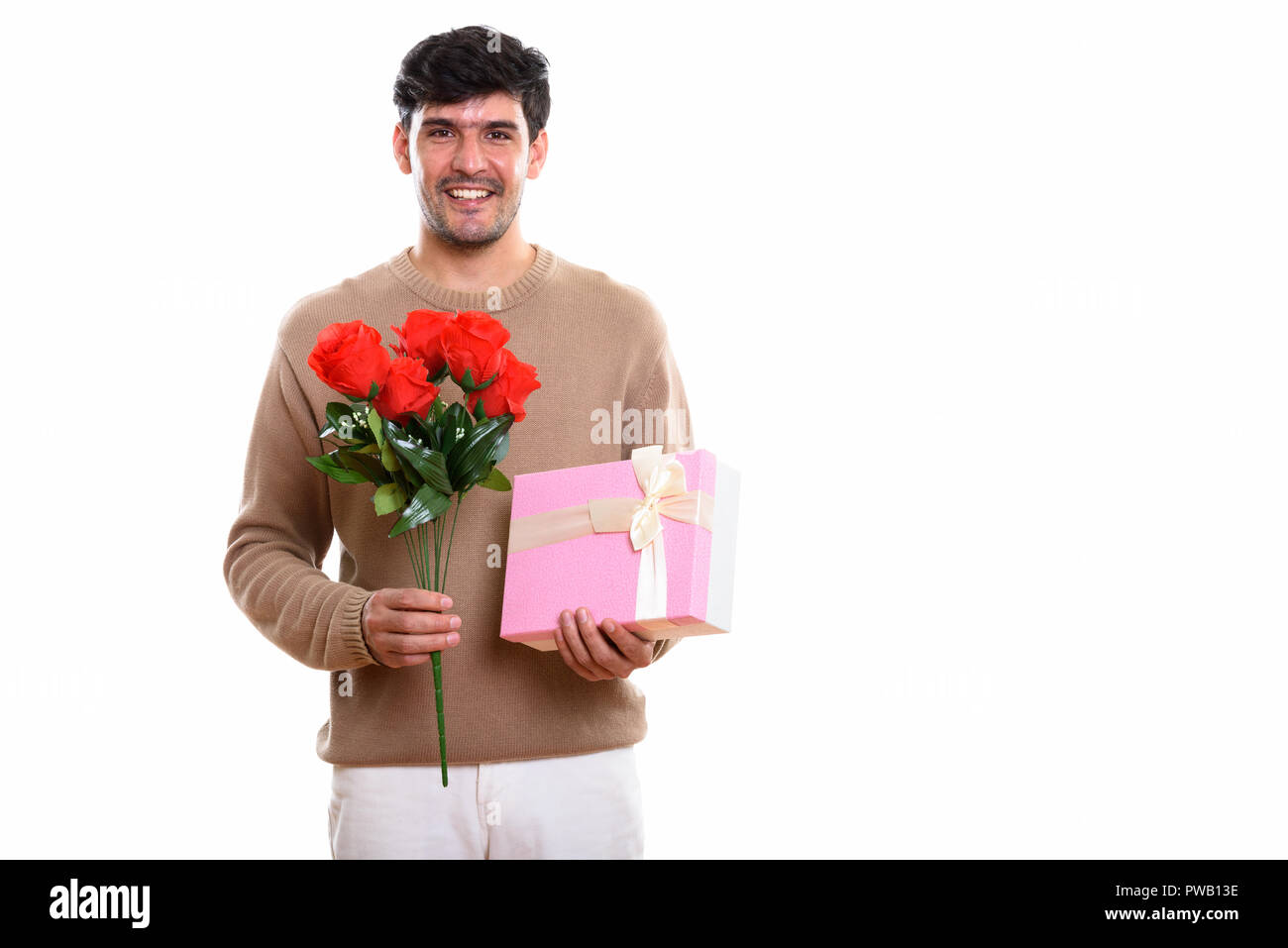 Giovani felici persiano uomo sorridente tenendo rose rosse e regalo Foto Stock