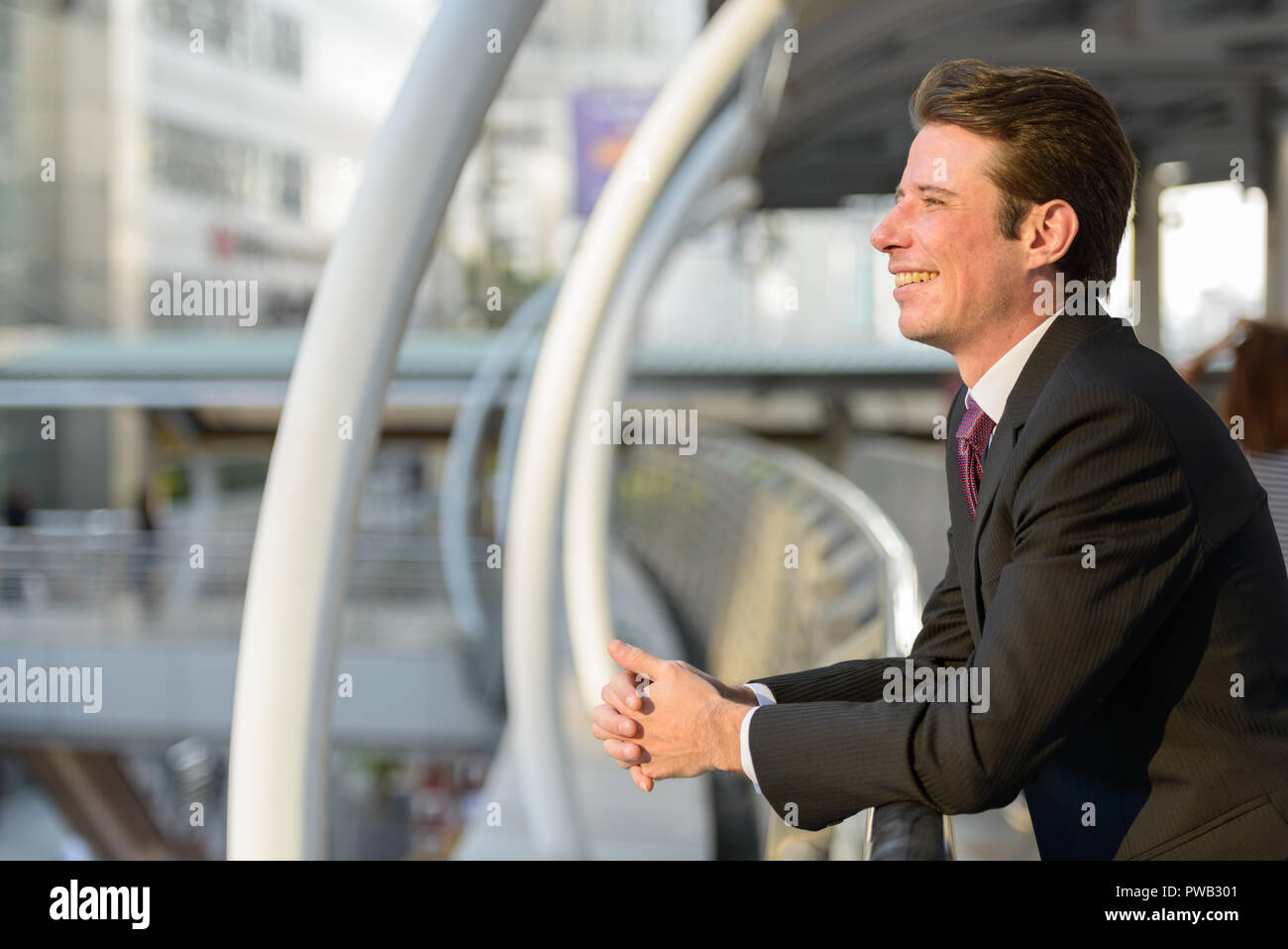 Vista di profilo di happy businessman sorridente e pensare in footbr Foto Stock