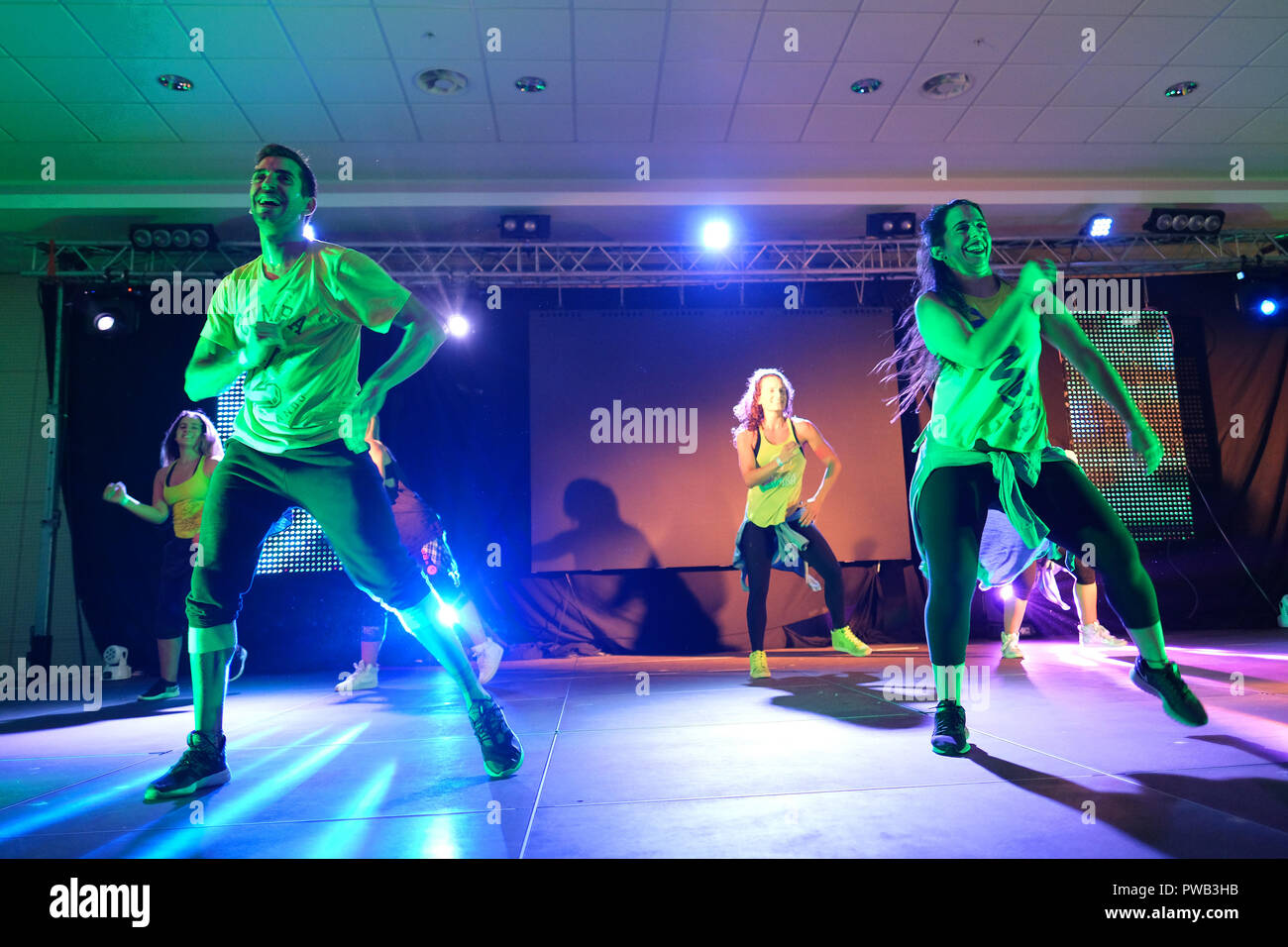 Gli istruttori dancing energicamente sul palco durante una classe Zumba Foto Stock