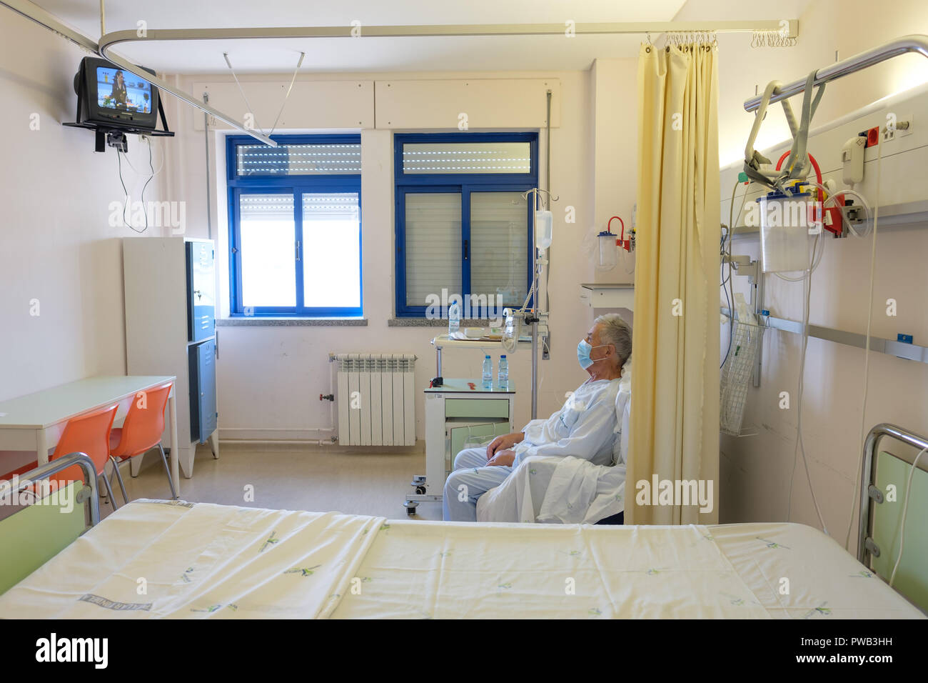 Paziente che indossa la maschera mentre è seduto in un ospedale camera da letto Foto Stock