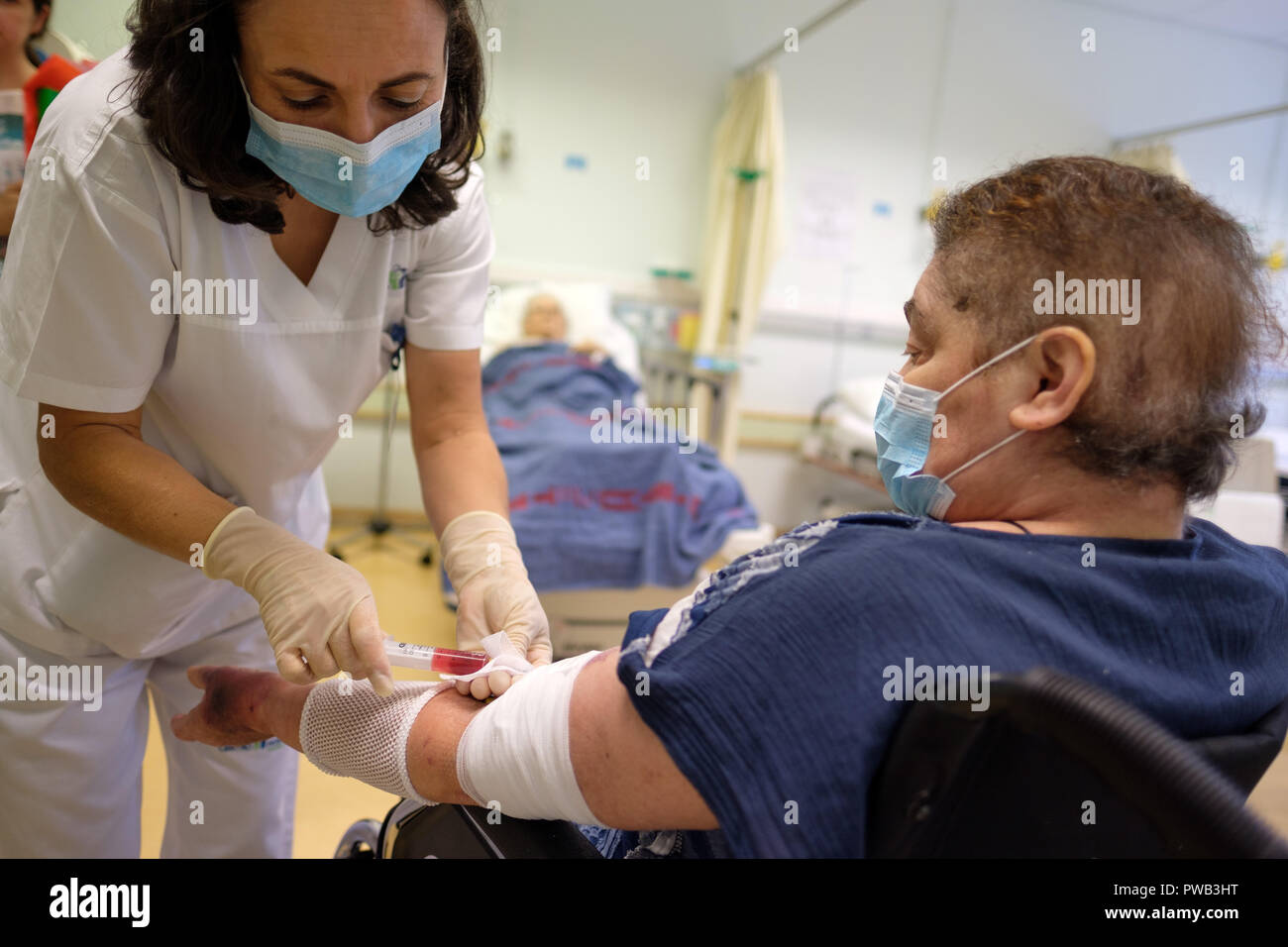 L'infermiera tenendo campione di sangue dal paziente anziano in un ospedale Foto Stock