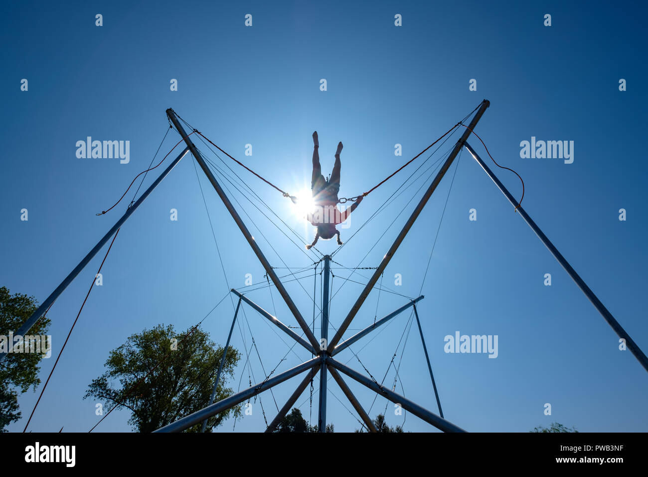 Giovane ragazza nel cavo saltando su un trampolino mentre è collegato con cavi bungee Foto Stock