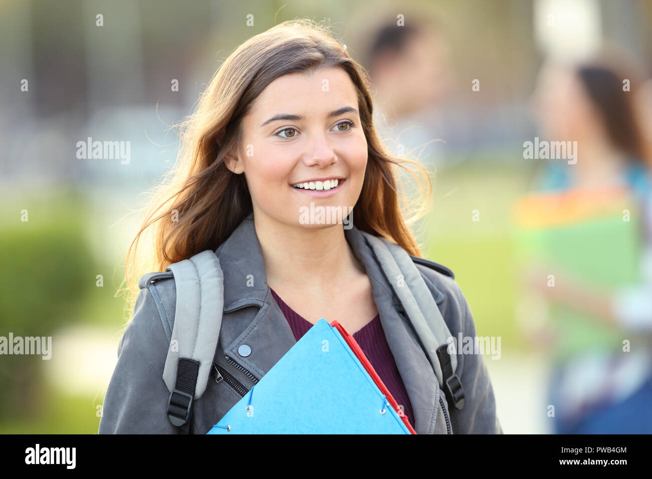 Felice studente a piedi in un campus universitario con altre persone in background Foto Stock