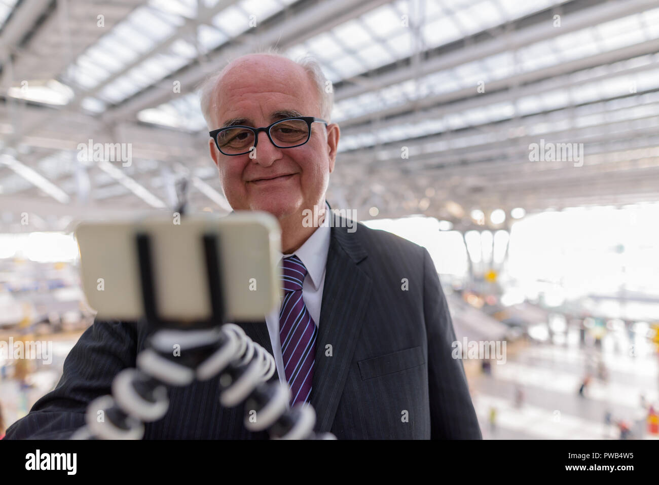 In sovrappeso imprenditore senior lounging intorno all'aeroporto di divieto Foto Stock