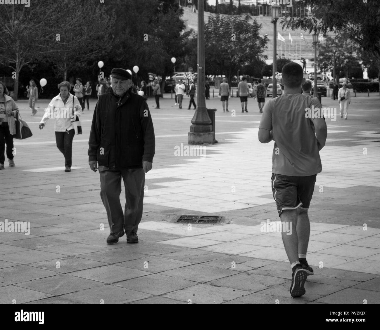 Un giovane uomo è correre verso il vecchio stadio olimpico, un vecchio è a breve distanza da esso, Atene Grecia. Foto Stock