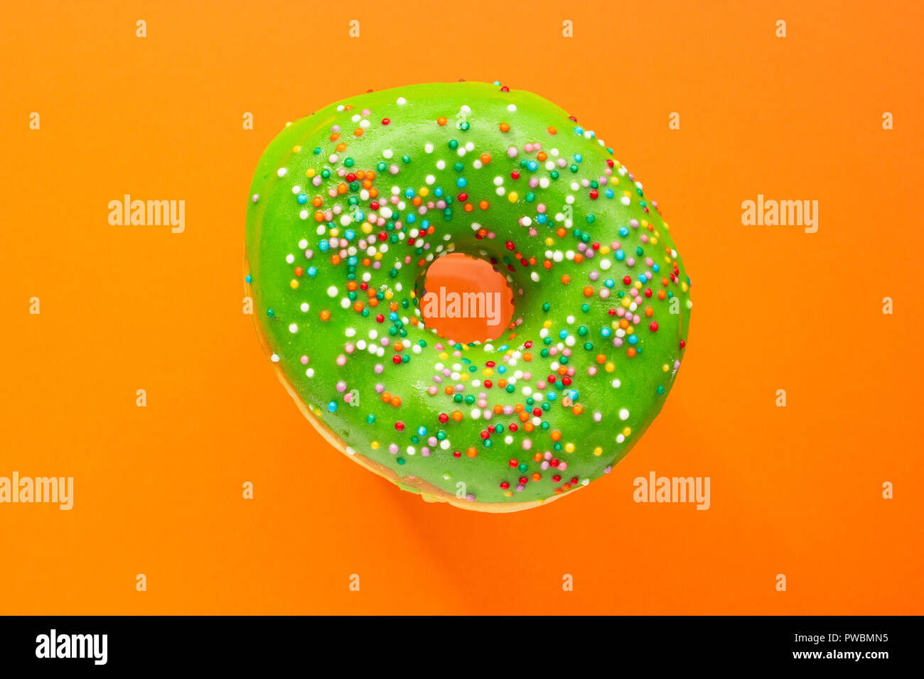 Donut verde con spruzzino isolato su sfondo arancione, close-up Foto Stock