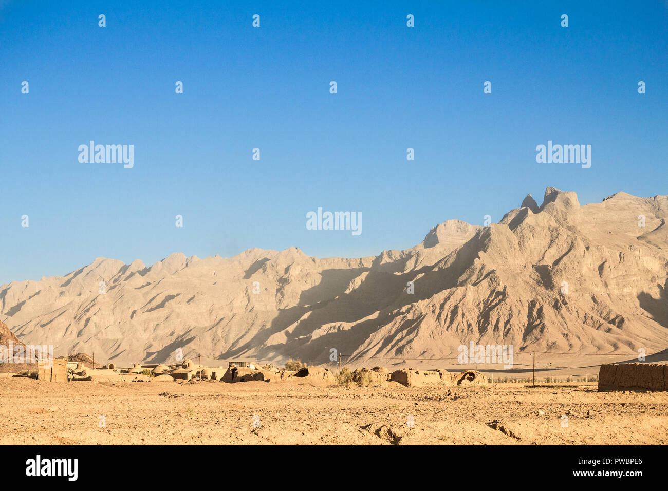 Abbandonato il vecchio villaggio iraniano nel deserto vicino la città di Yazd, fatta di muri di argilla e case di argilla, mezza distrutta, circondato da montagne rocciose hi Foto Stock