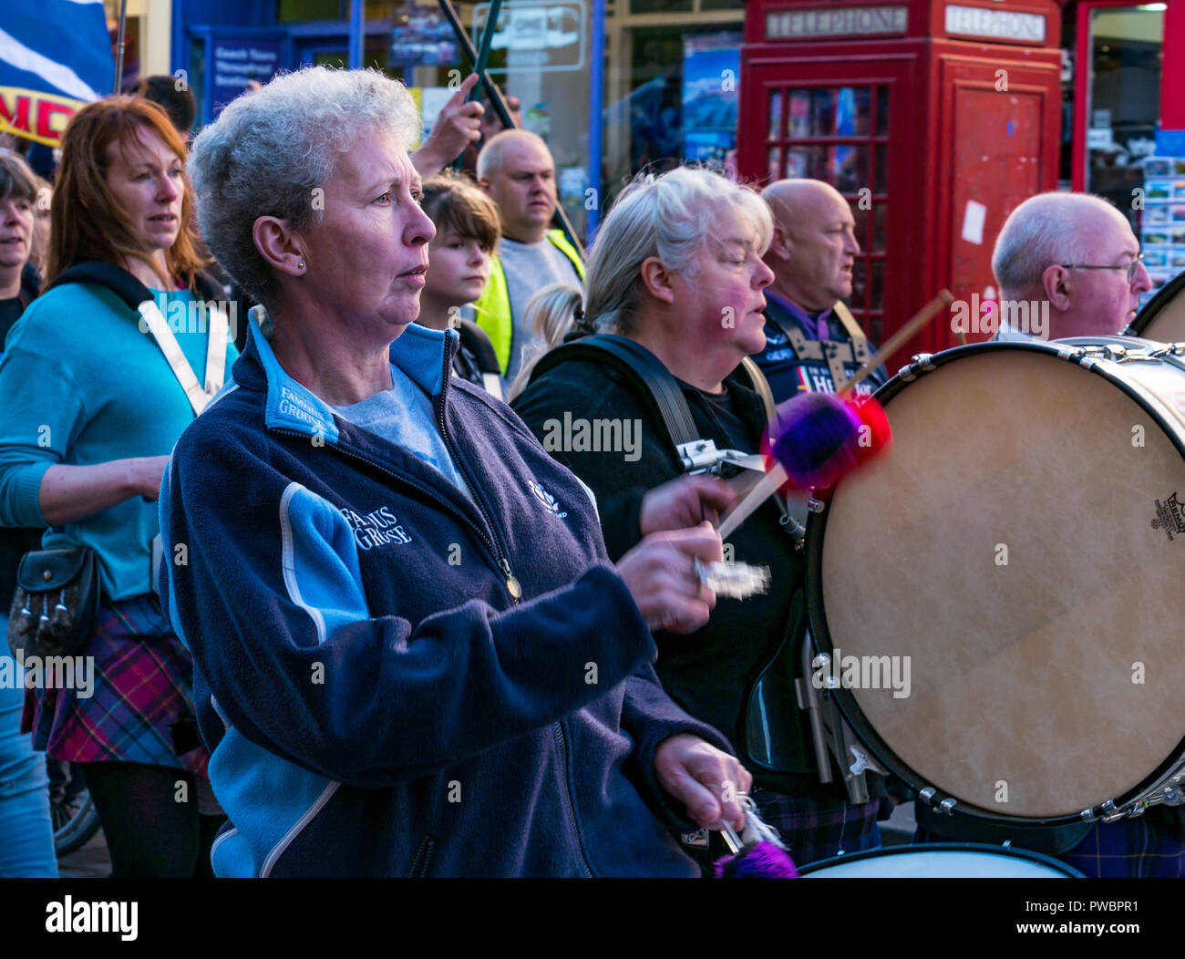 Donna drumming e marciando a Tutti sotto uno striscione indipendenza scozzese AUOB marzo 2018, Royal Mile di Edimburgo, Scozia, Regno Unito Foto Stock