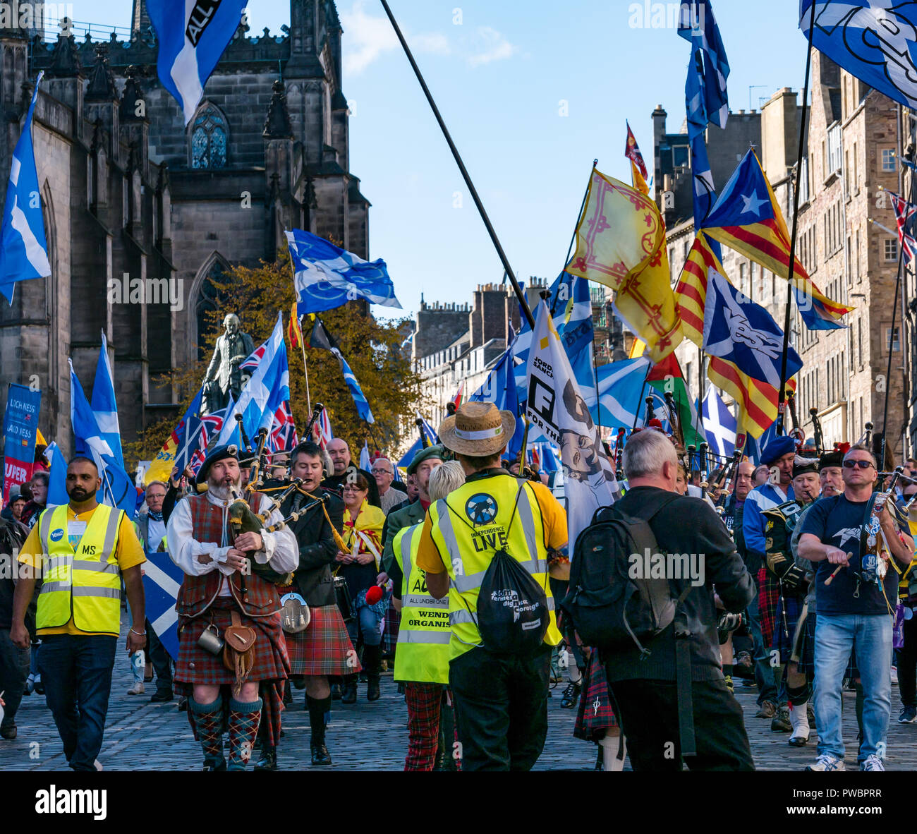 Manifestanti e sventolando bandiere nazionali a tutti sotto uno striscione AUOB indipendenza scozzese marzo 2018, Royal Mile di Edimburgo, Scozia, Regno Unito Foto Stock