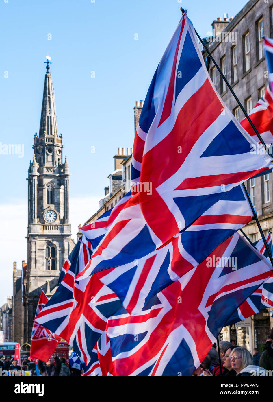 Union Jack sventolando bandiere con Tron Kirk guglia di clock, indipendenza scozzese Tutti sotto uno striscione AUOB marzo 2108, Royal Mile di Edimburgo, Scozia, Regno Unito Foto Stock